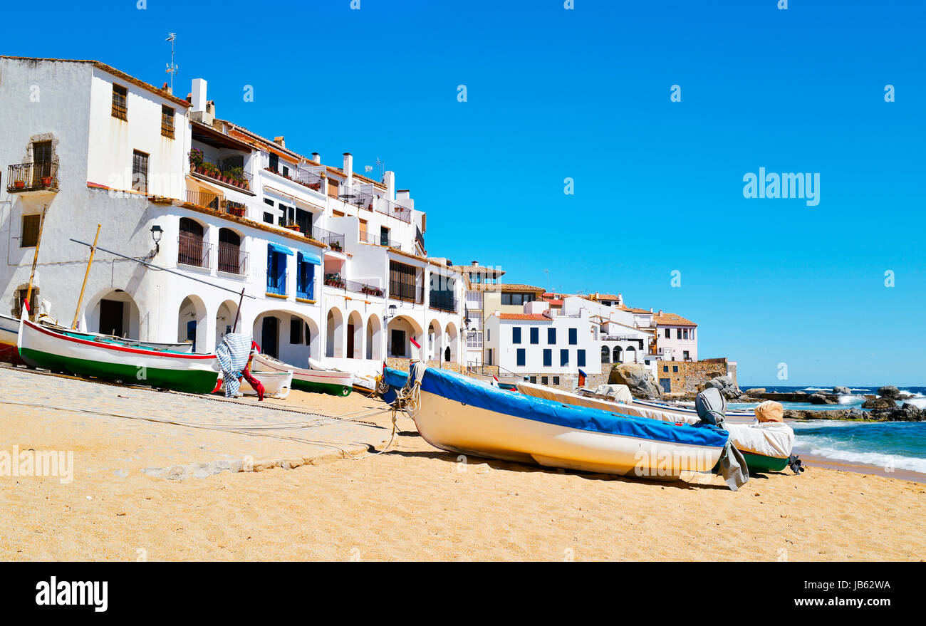 some old fishing boats stranded on the Barques Beach in Calella de Palafrugell, Costa Brava, Catalonia, Spain, with its characteristics white houses w Stock Photo