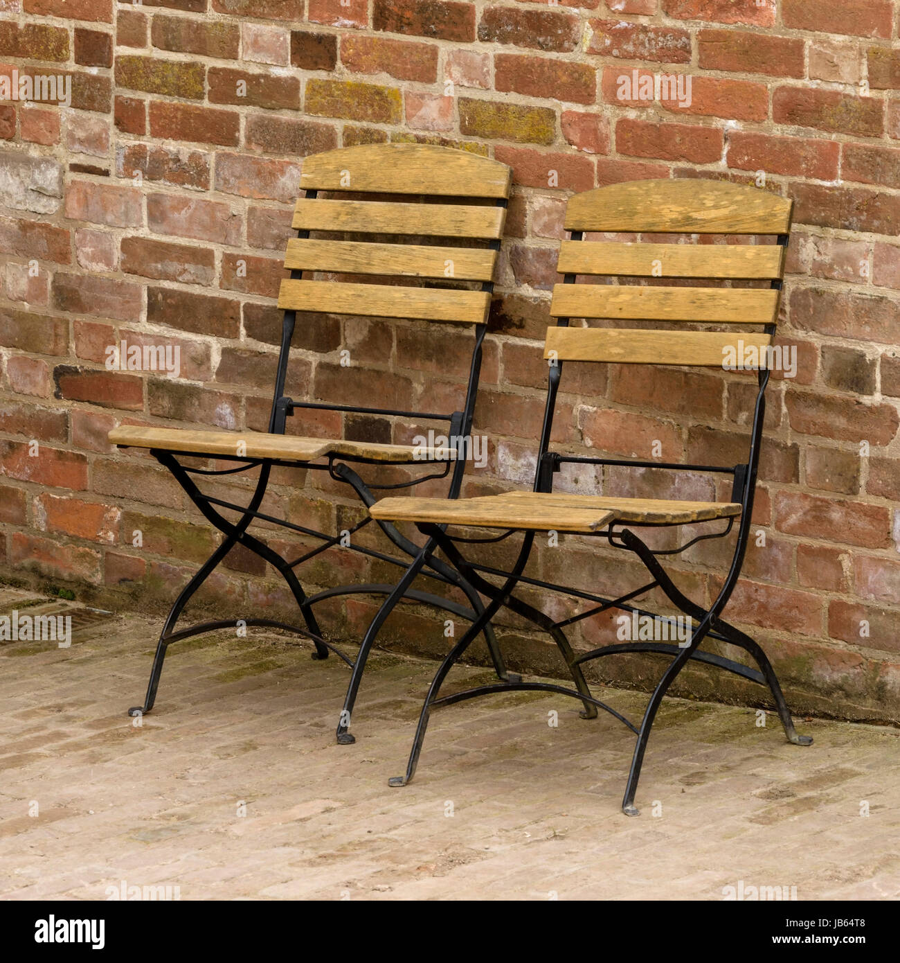 Two Folding Metal Chairs With Wooden Slats In Front Of Red Brick Wall Stock Photo Alamy