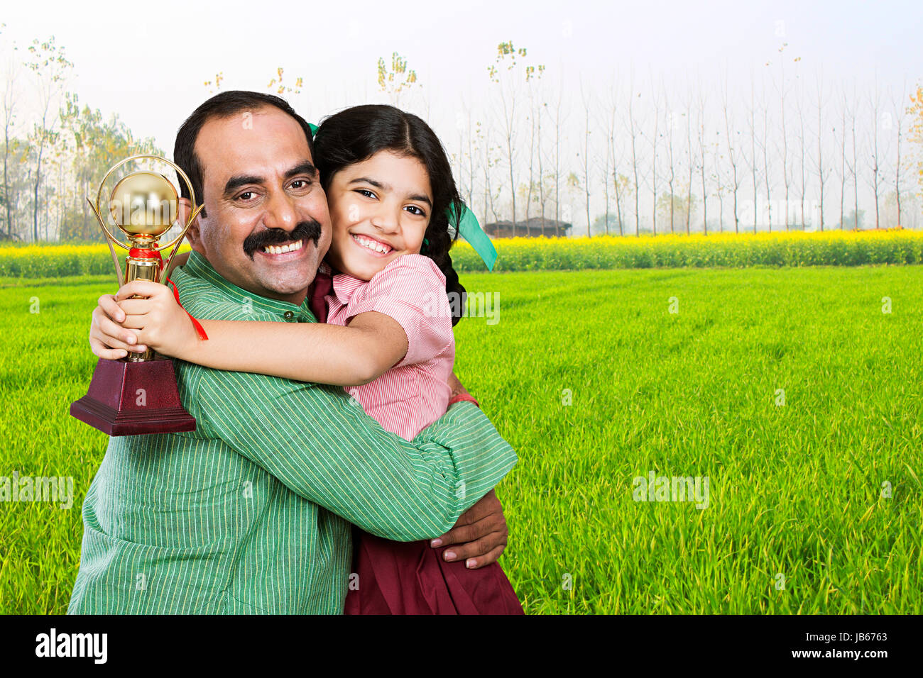 Happy 2 Indian Rural Father Hugging Kid Daughter Winning Trophy Celebration In Field Stock Photo