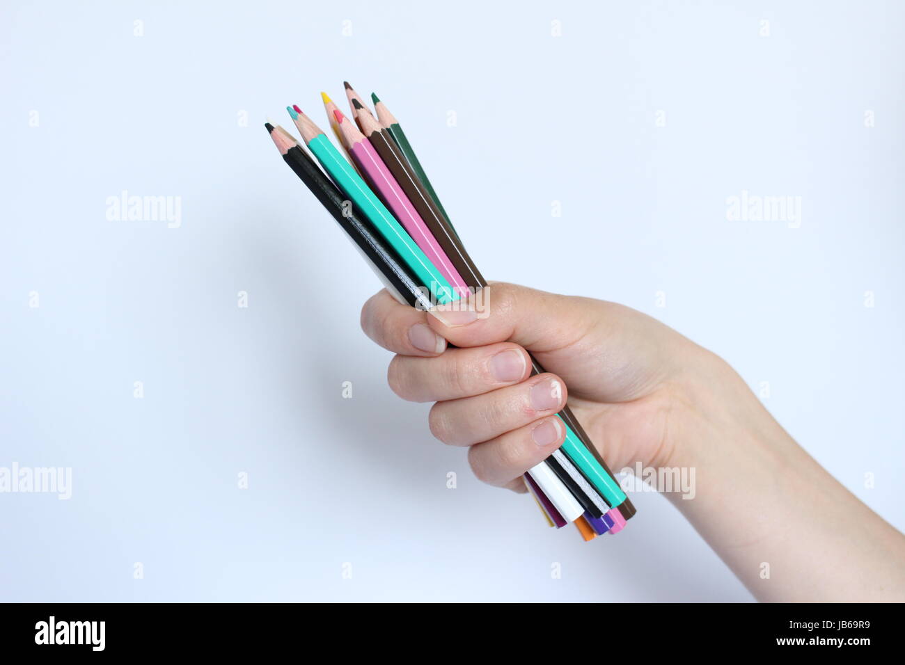 A hand filled with colored pencils on a white background Stock Photo