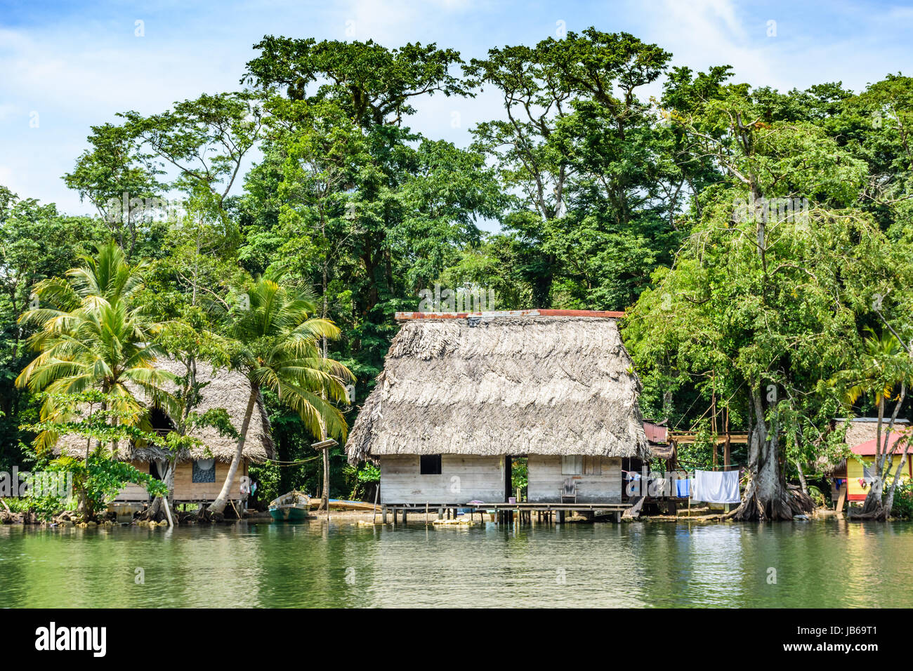 Rio Dulce, Guatemala - September 1, 2016: Wooden houses on stilts with palm leaf roofs on riverbank of the Rio Dulce in Guatemala, Central America Stock Photo