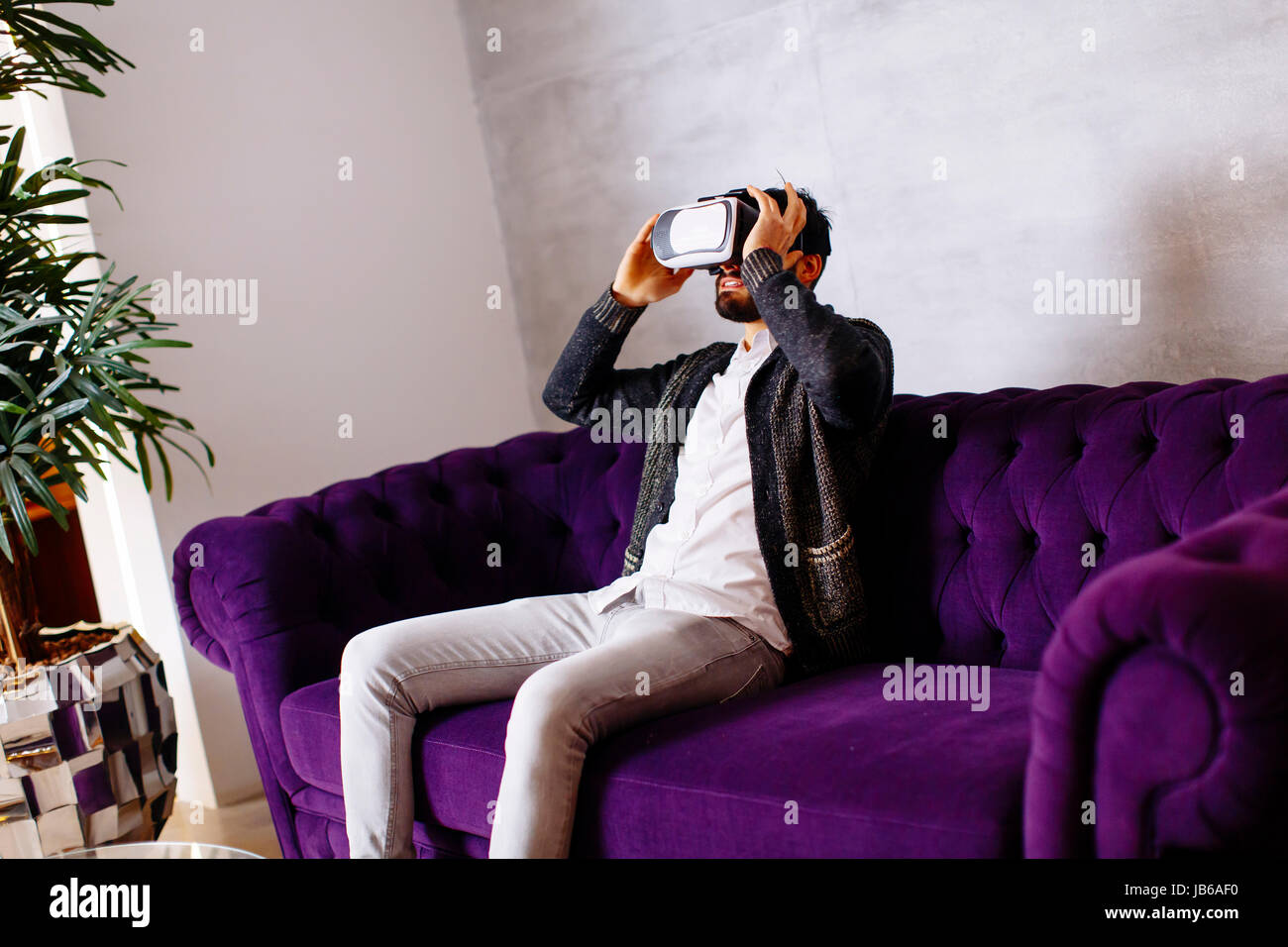 Closeup of bearded young man wearing virtual reality goggles in modern ...