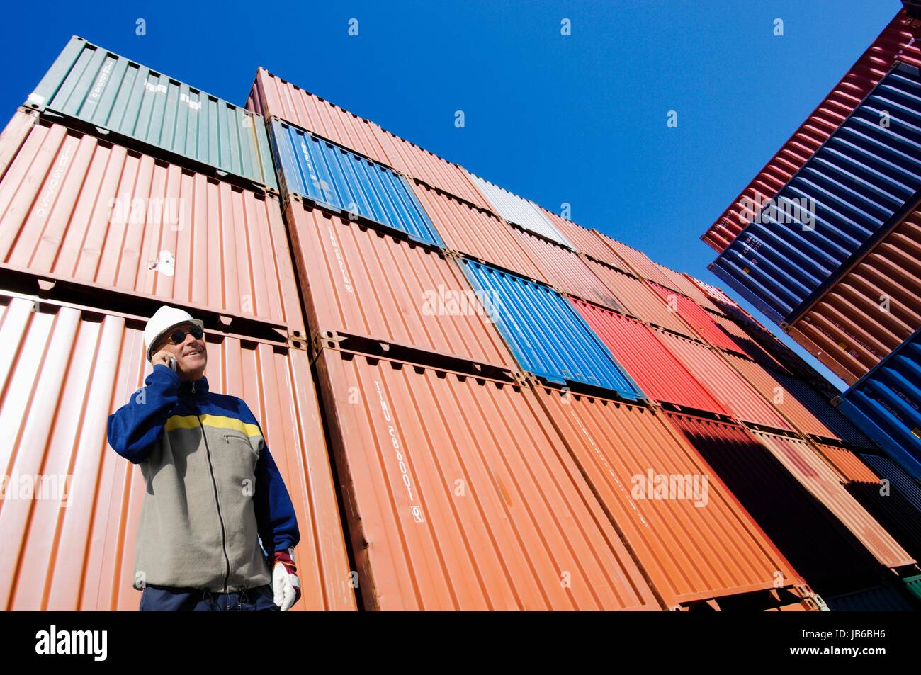 MODEL RELEASED. Man on cell phone with shipping containers. Stock Photo