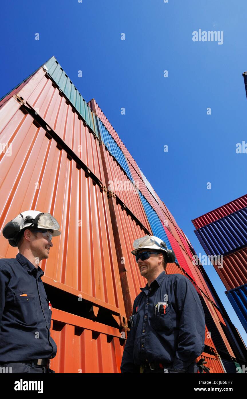 MODEL RELEASED. Two industrial workers with shipping containers. Stock Photo