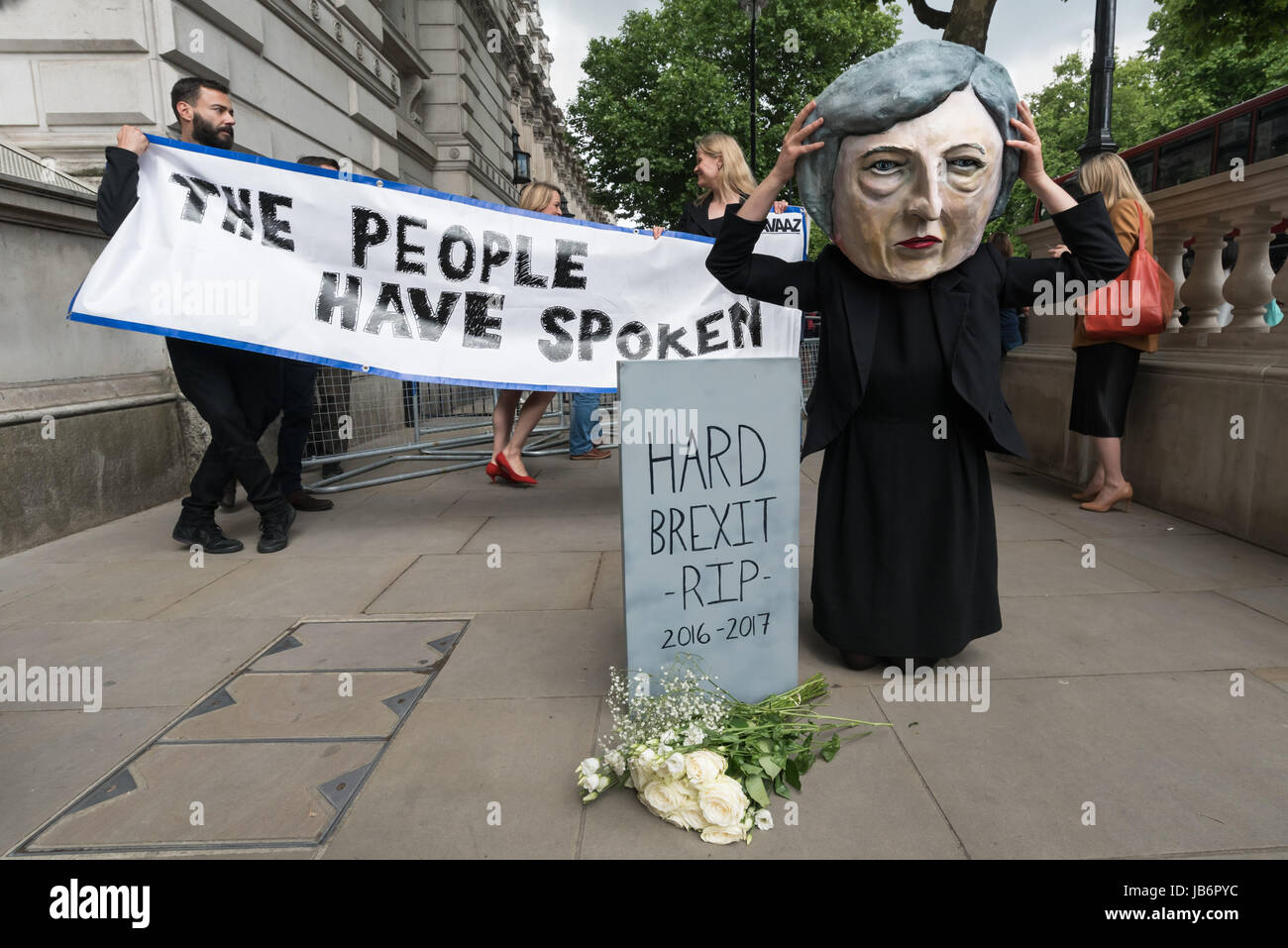 London, UK. 9th June 2017. After election results showed that no party had a majority, protesters came to Westminster to demand that Theresa May resign. She is intending to stay on and try and govern, relying on votes from the DUP party, linked to loyalist paramilitaries. Avaaz brought a person with a large caricature head of Theresa May to Downing St to pose in front of a banner 'The People Have Spoken' and lay white roses in front of a gravestone with the message 'Hard Brexist R.I.P 2016-2017'. Credit: ZUMA Press, Inc./Alamy Live News Stock Photo