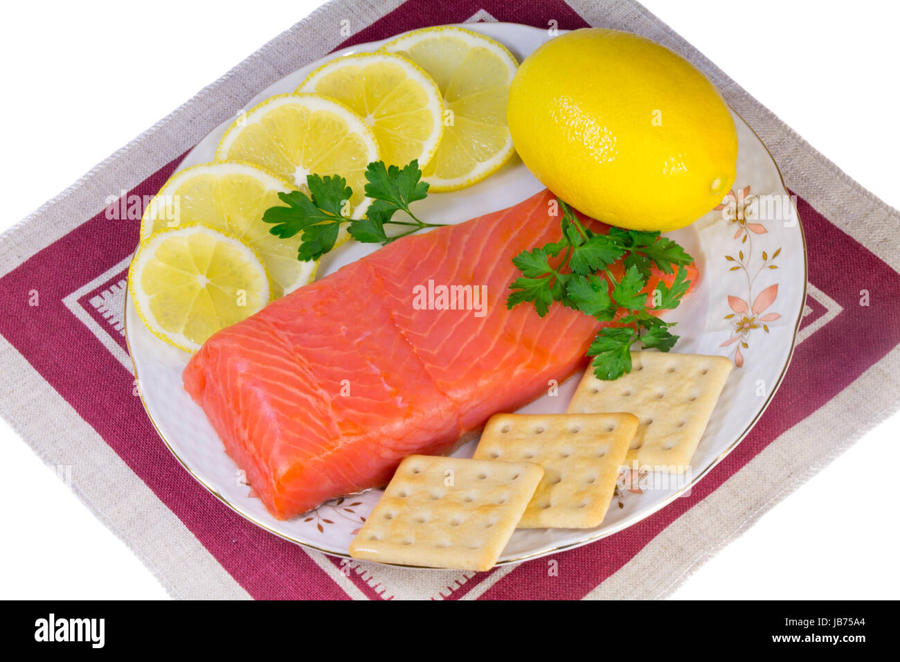 On a platter lie salmon fillet, lemons, sliced and whole, biscuits, fresh herbs parsley. Presented on a white background. Stock Photo