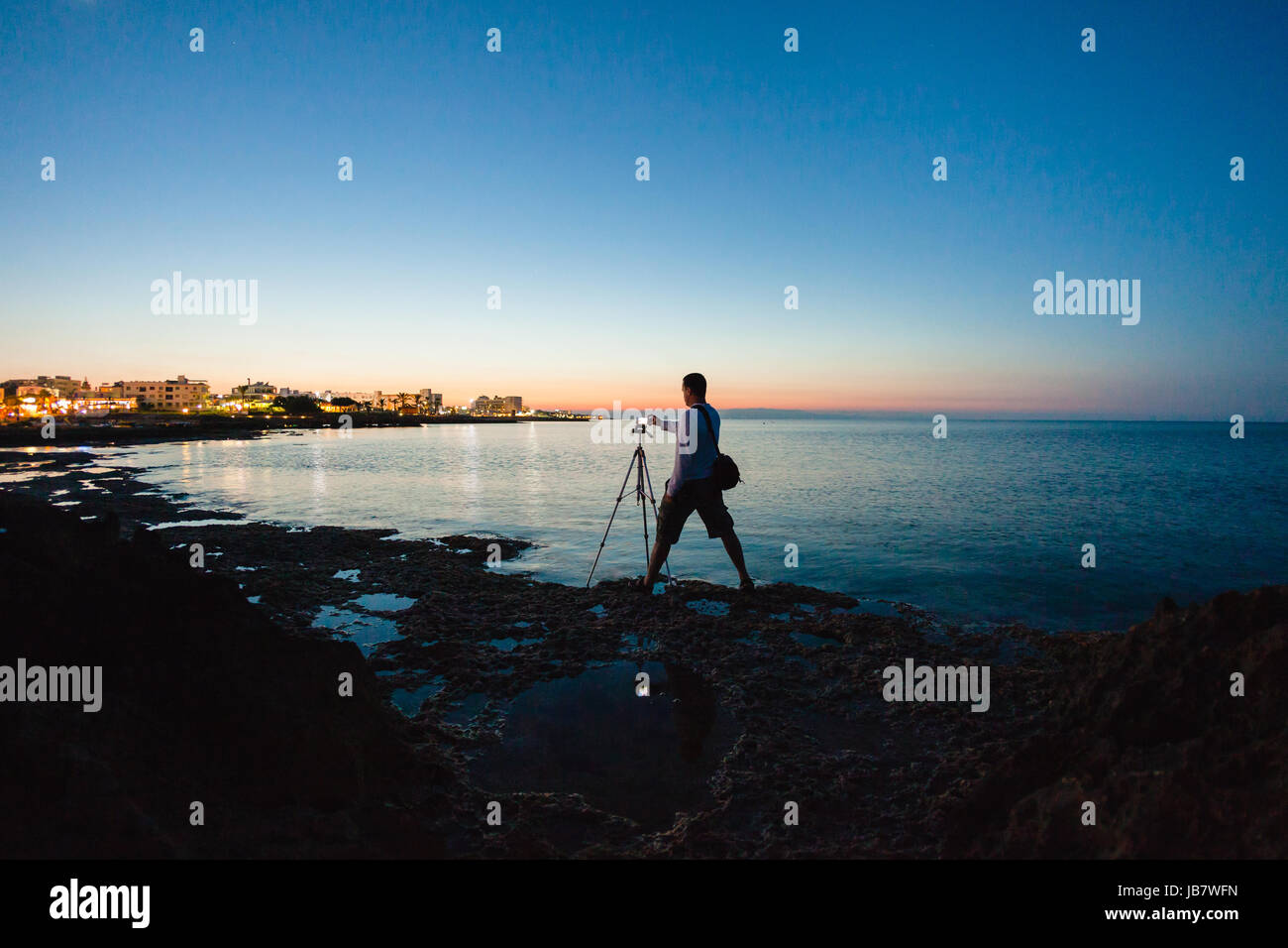 Photographer taking a photo of a beautiful sea view by his camera on a ...