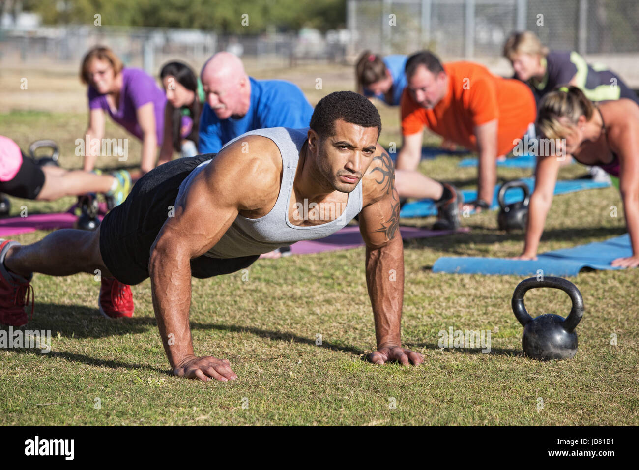 Group of serious adults doing push-ups outdoors Stock Photo