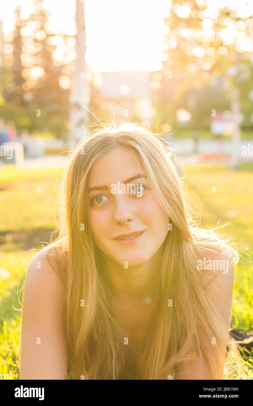 Portrait of a young woman lying on the grass in sunlight Stock Photo ...