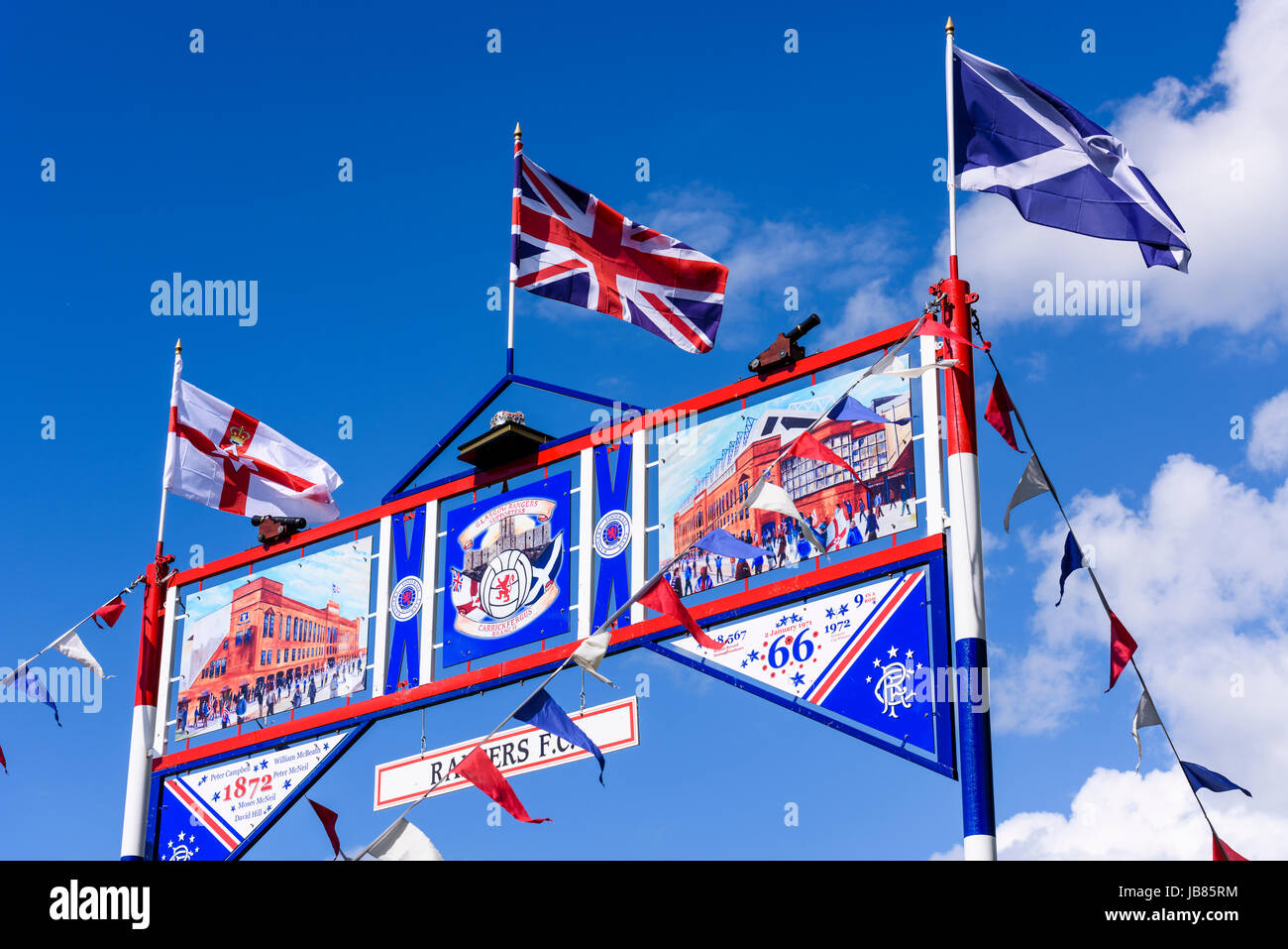 Red white and blue archway commemorating Rangers Football Club with the Northern Ireland, Union and Scottish Saltire flags. Stock Photo