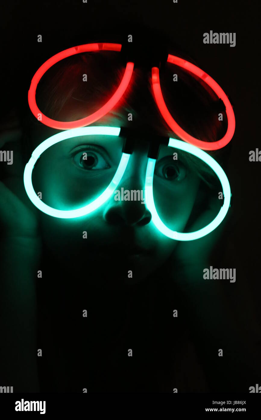 Girl wearing glowing neon glasses made from glow sticks for halloween Stock Photo