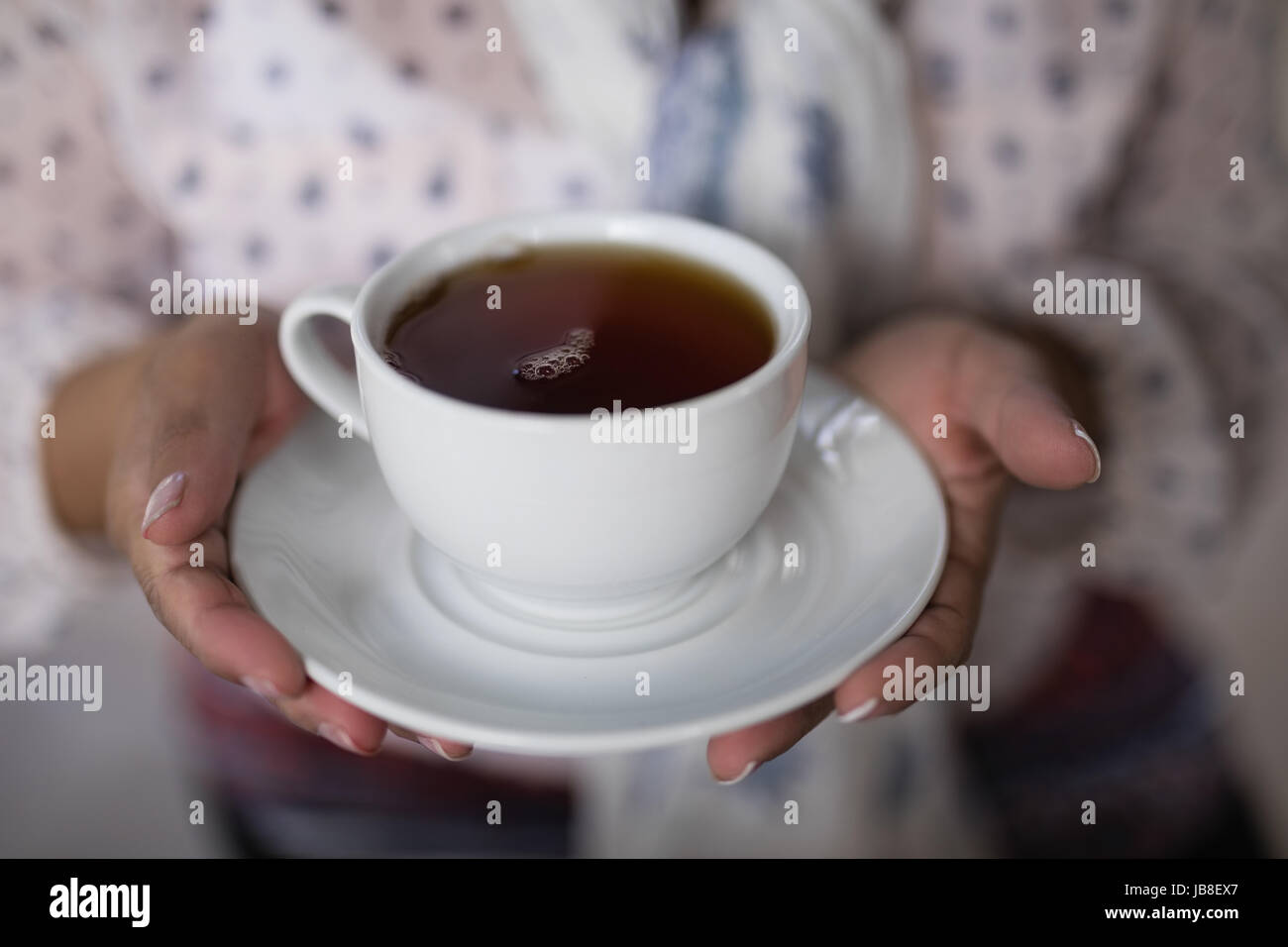 Mid section of woman holding tea cup at home Stock Photo