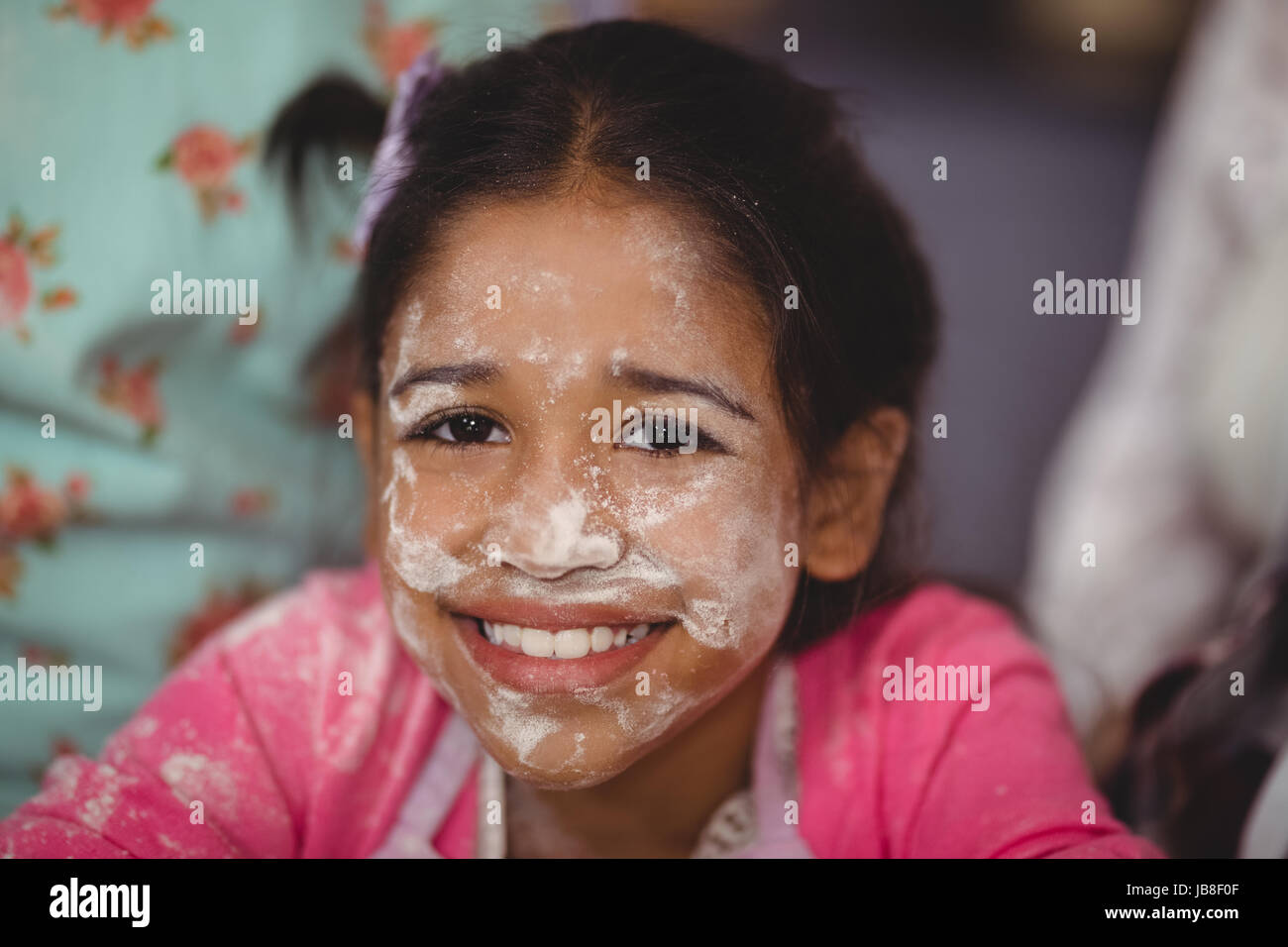 Portrait of smiling girl with flour on face at home Stock Photo