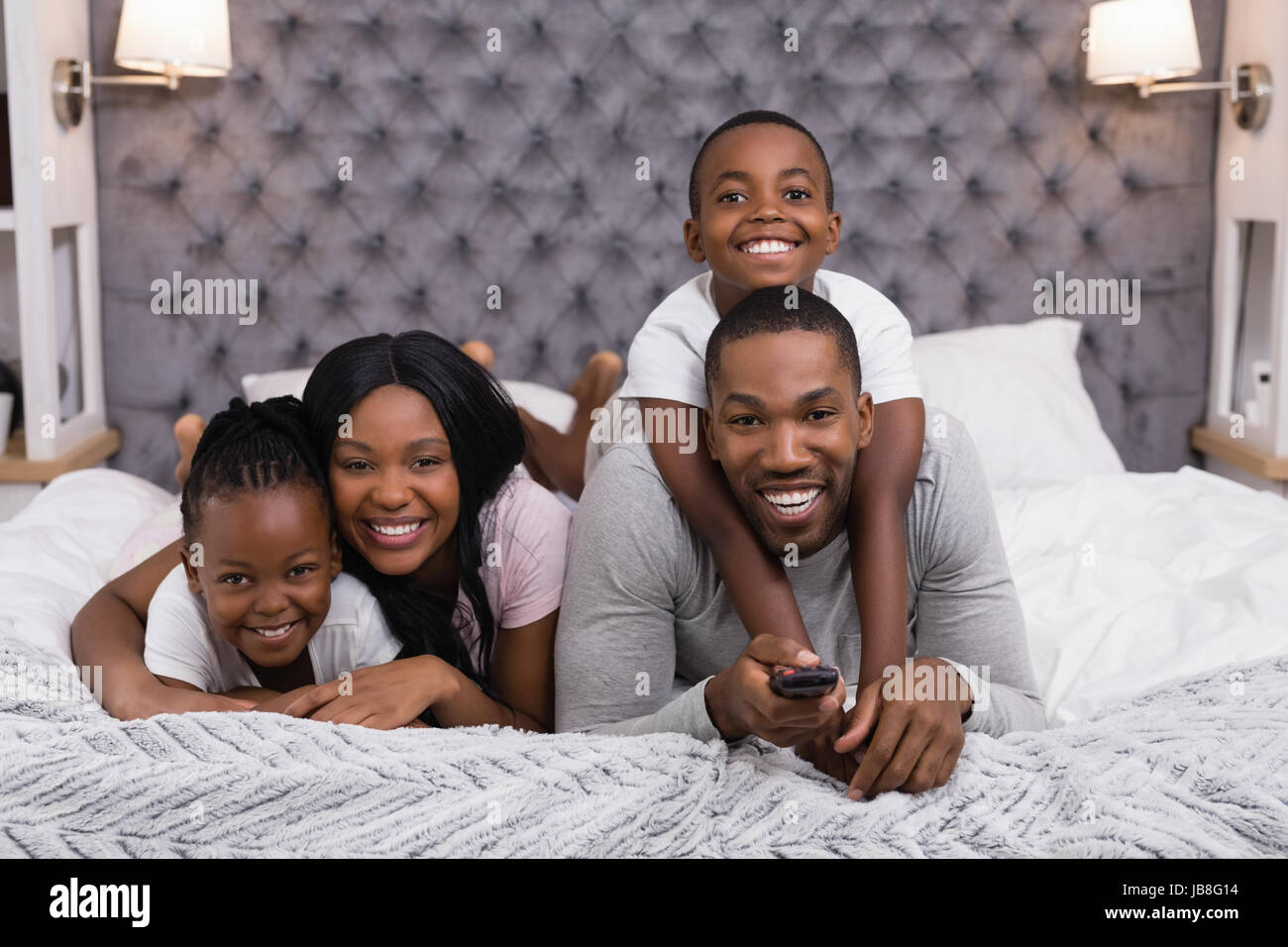 Portrait of happy family watching television while lying on bed at home Stock Photo