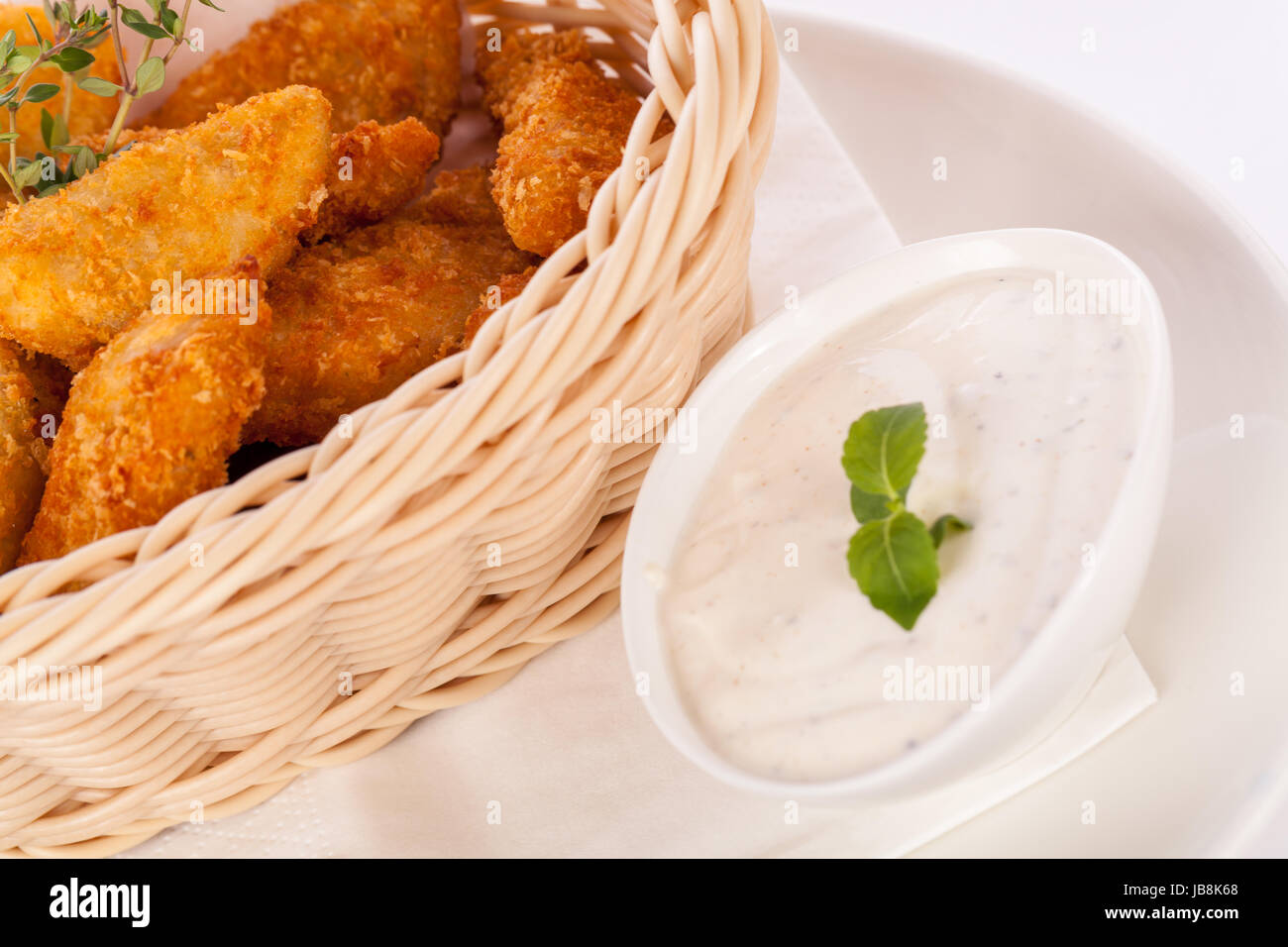 Frische hähnchenschlegel und nuggets golden frittiert in einem Korb isoliert vor weißem Hintergrund Stock Photo