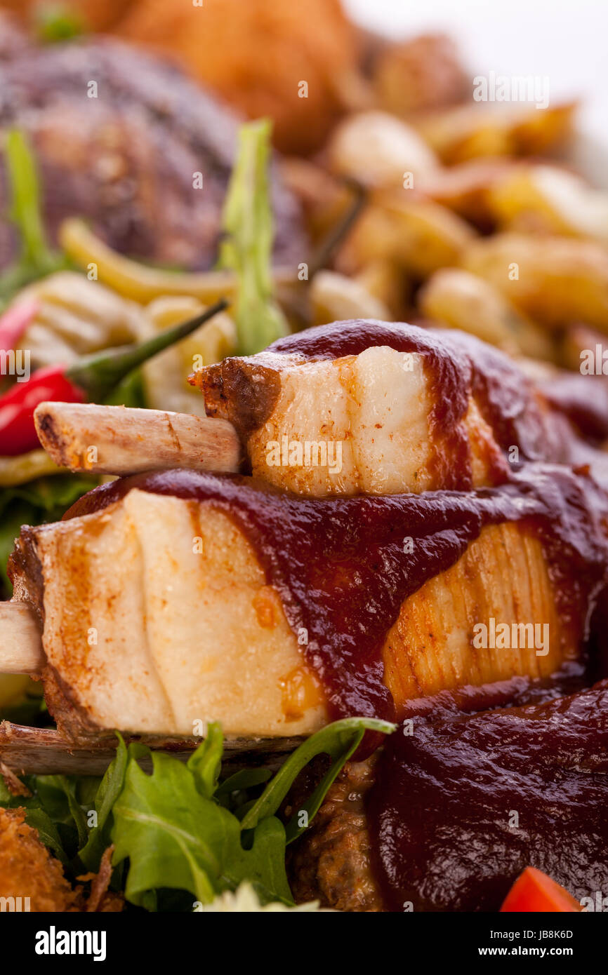 Riesige Barbecueplatte mit gemischtem Fleisch und Steaks auf Salat isoliert vor weißem Hintergrund Stock Photo