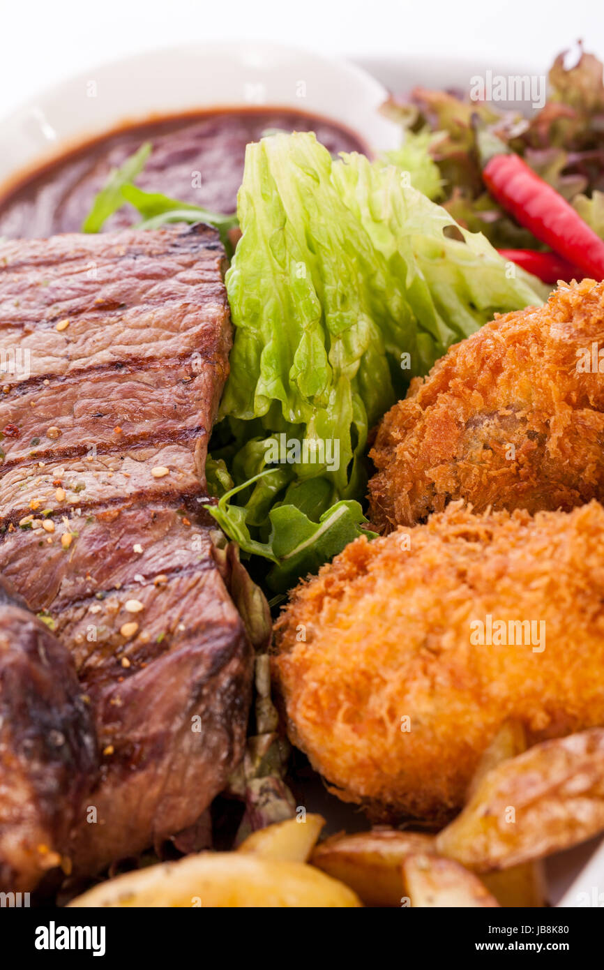 Riesige Barbecueplatte mit gemischtem Fleisch und Steaks auf Salat isoliert vor weißem Hintergrund Stock Photo