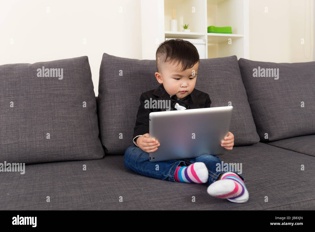 Little boy using digital tablet and sitting on sofa Stock Photo - Alamy