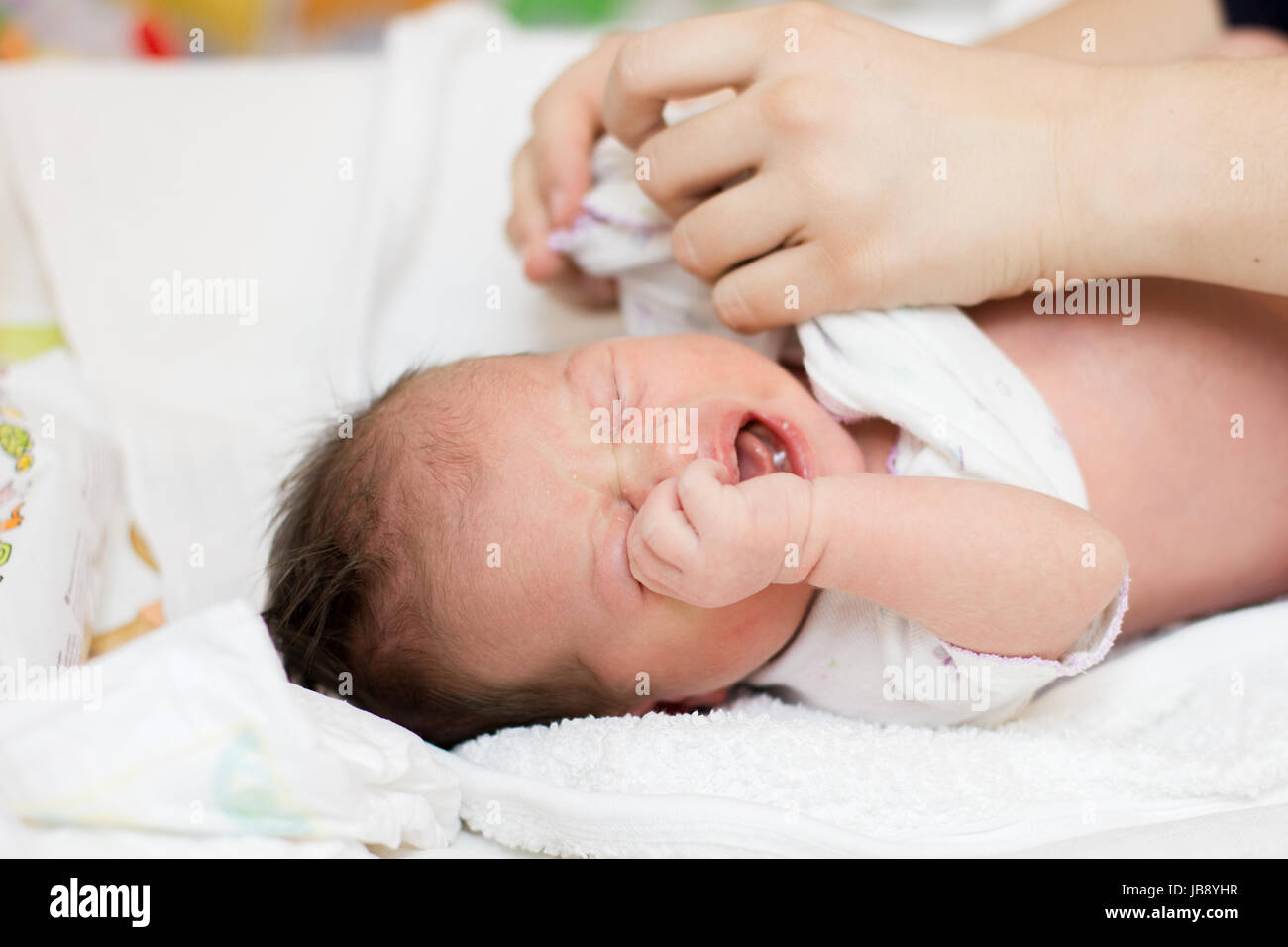 Mother's changing clothes of crying newborn baby Stock Photo Alamy