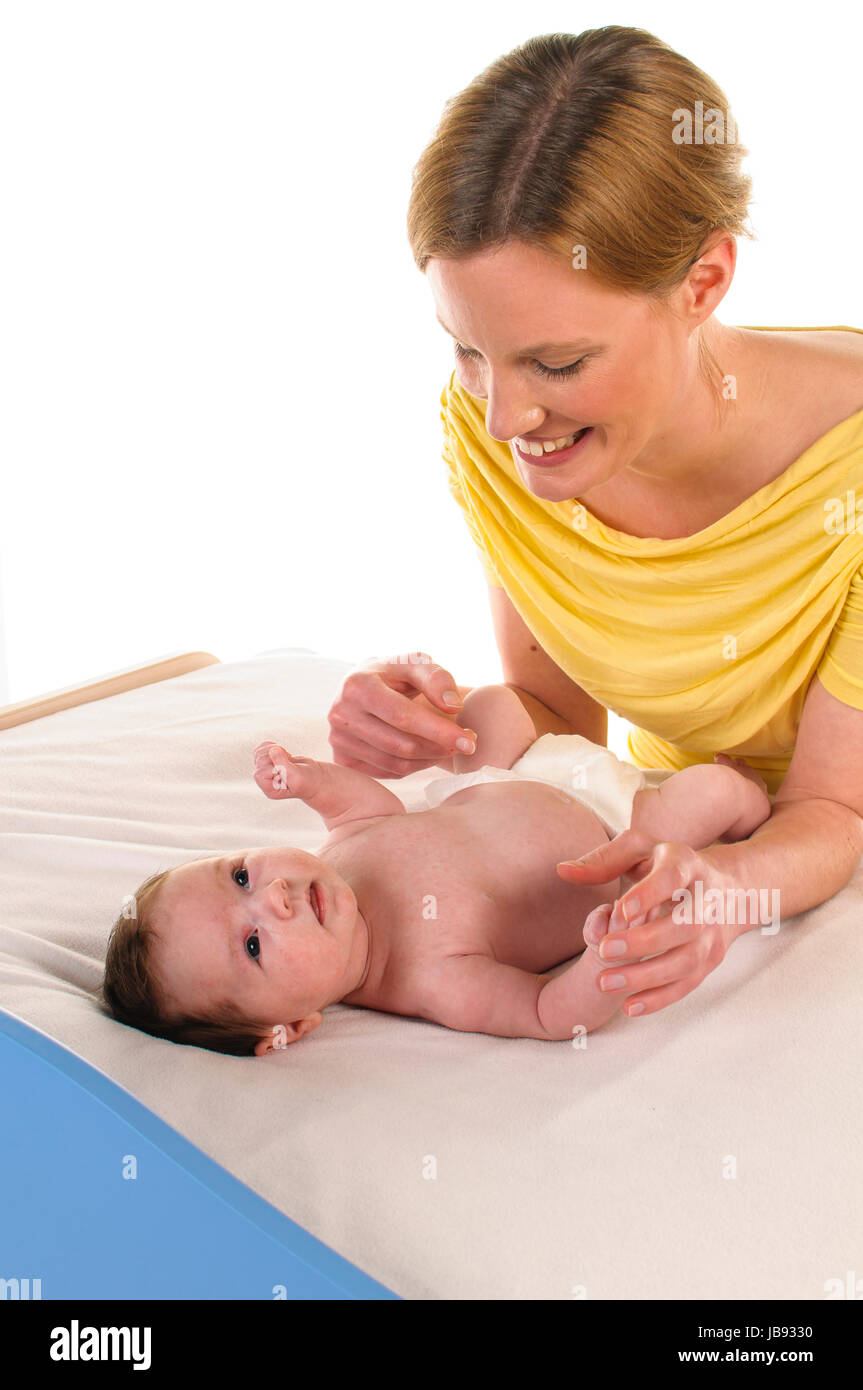 Mutter mit ihrem neugeborenem Baby betreibt Säuglingspflege an der Wickelkommode, freigestellt vor weißem Hintergrund. Stock Photo