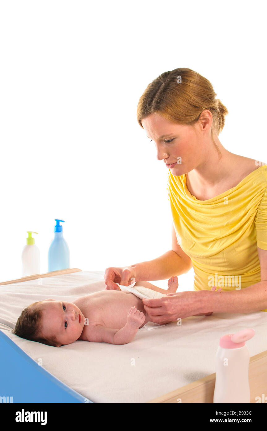 Mutter mit ihrem neugeborenem Baby betreibt Säuglingspflege an der Wickelkommode, freigestellt vor weißem Hintergrund. Stock Photo