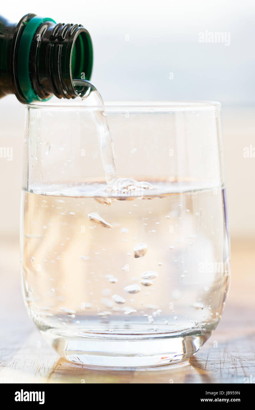 mineral water pouring into glass from green bottle Stock Photo Alamy