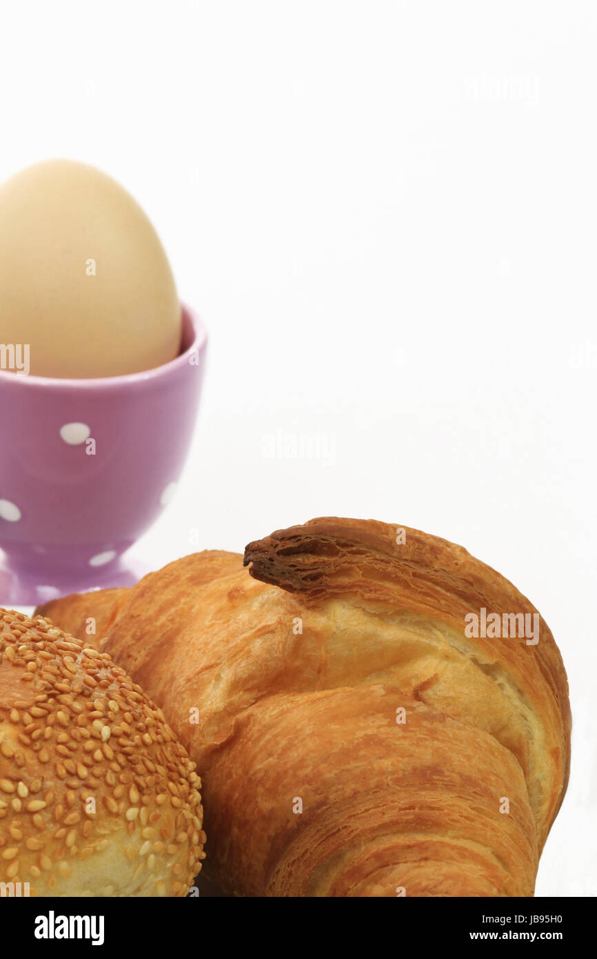 Ausschnitt eines Frühstückstisches mit Brötchen, Croissant und Ei im Eierbecher Stock Photo
