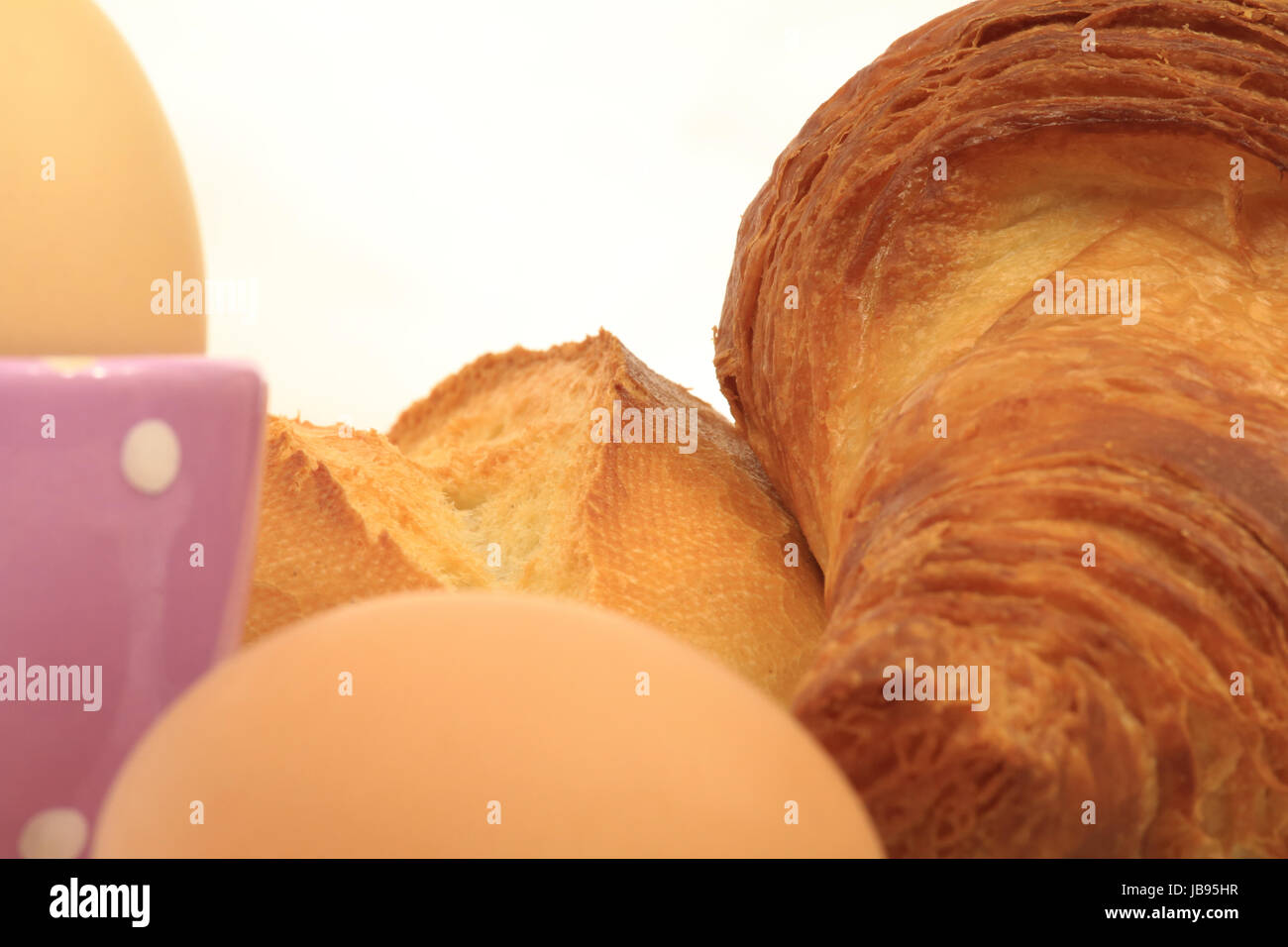 Ausschnitt eines Frühstückstisches mit Croissant, Brötchen, Eiern und Eierbecher Stock Photo