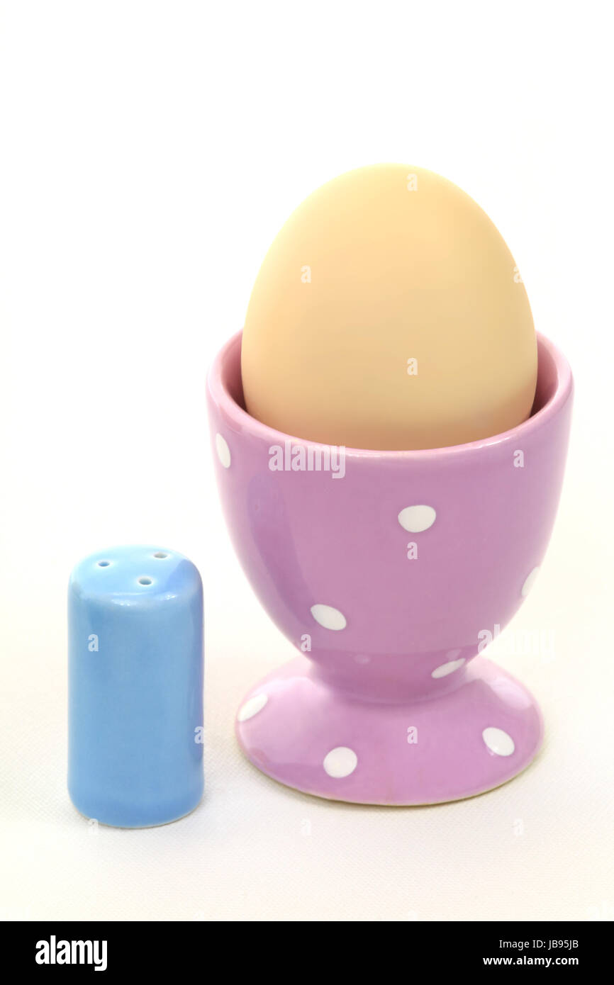 Ausschnitt eines Frühstückstisches mit Ei im Eierbecher und kleinem Salzstreuer Stock Photo