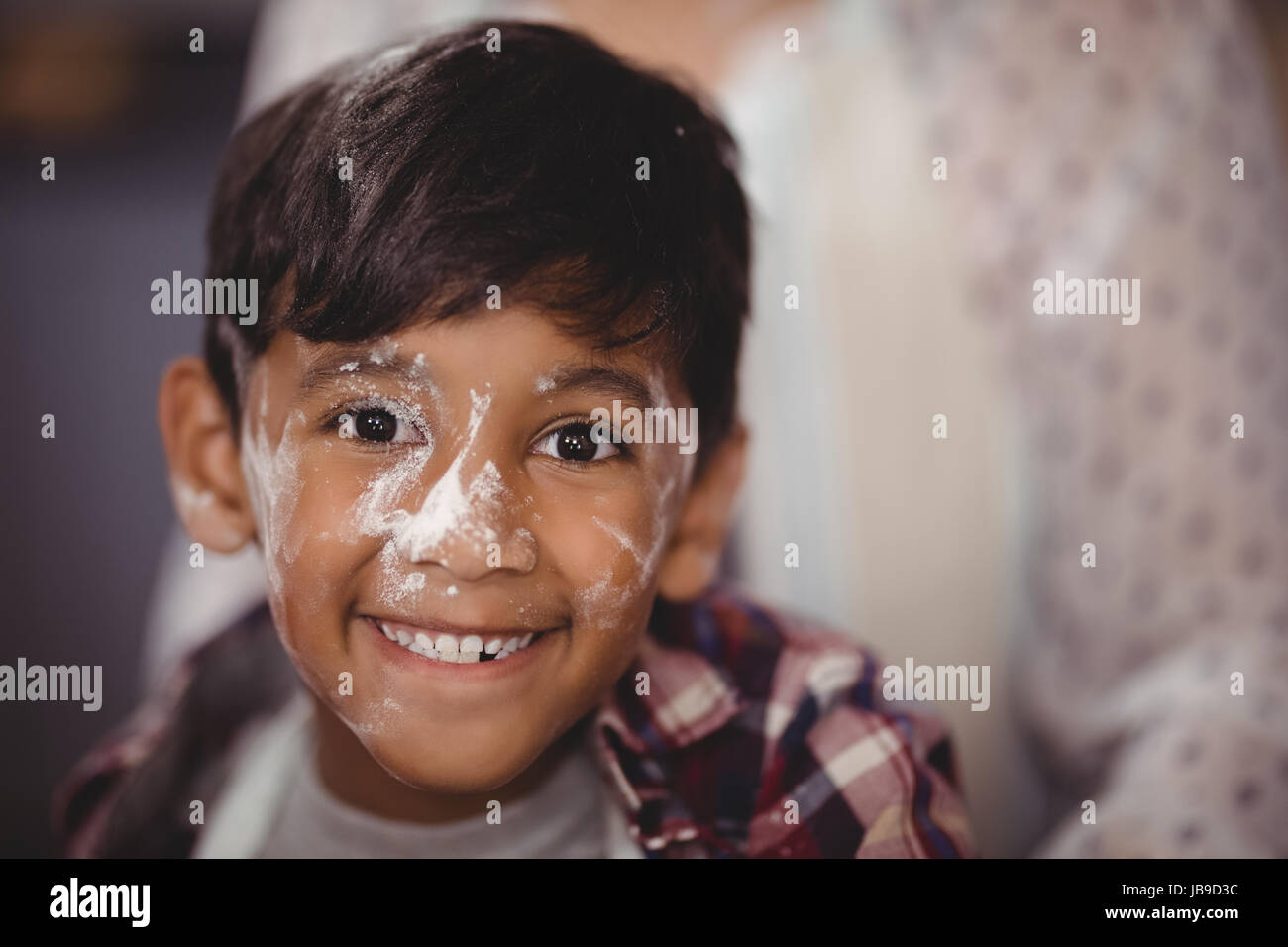 Portrait of smiling boy with flour on face at home Stock Photo