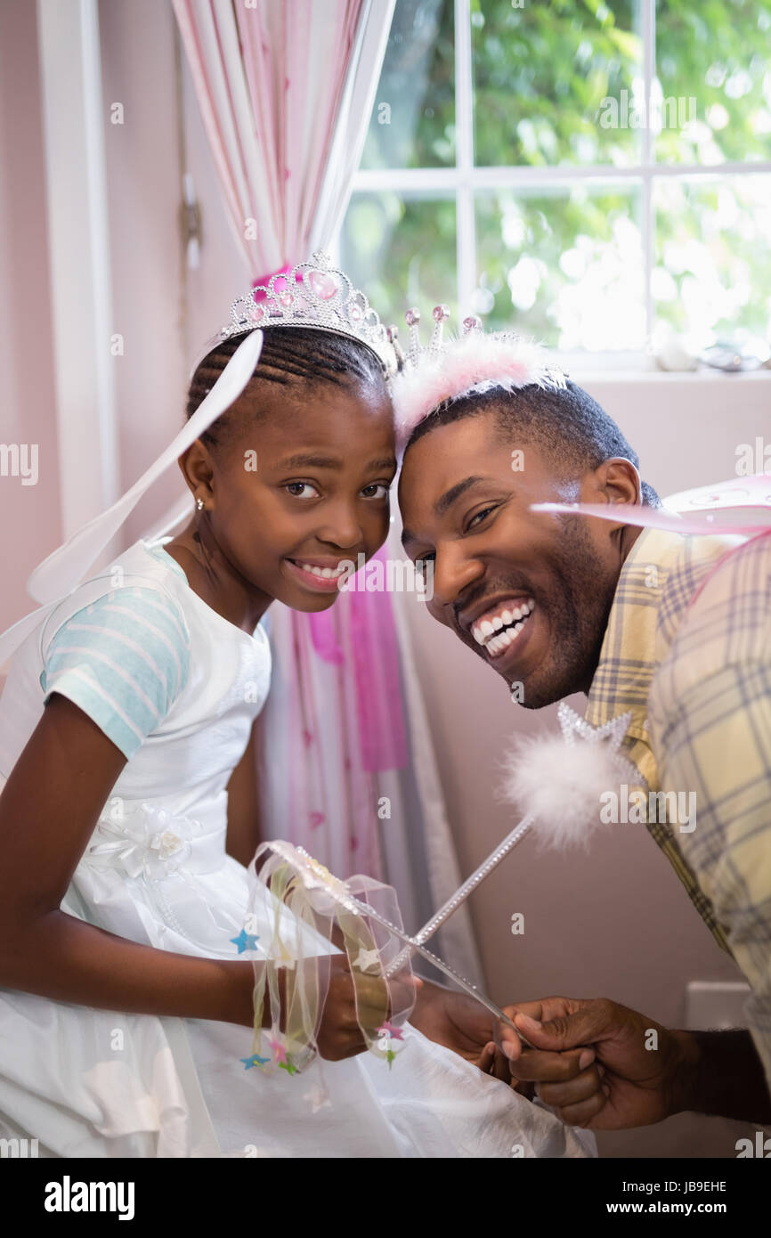 Portrait of cheerful father and daughter holding wands while wearing costumes Stock Photo