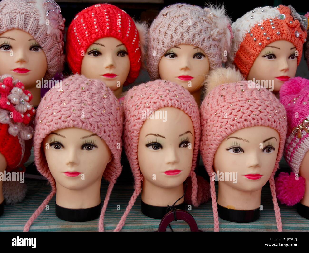 Close up of rows of identical vintage expressionless female mannequin heads wearing similar hand-knitted woollen hats Stock Photo