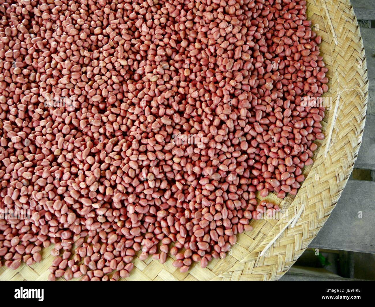Close up of part of large, flat , round basket full of peanuts in natural state Stock Photo