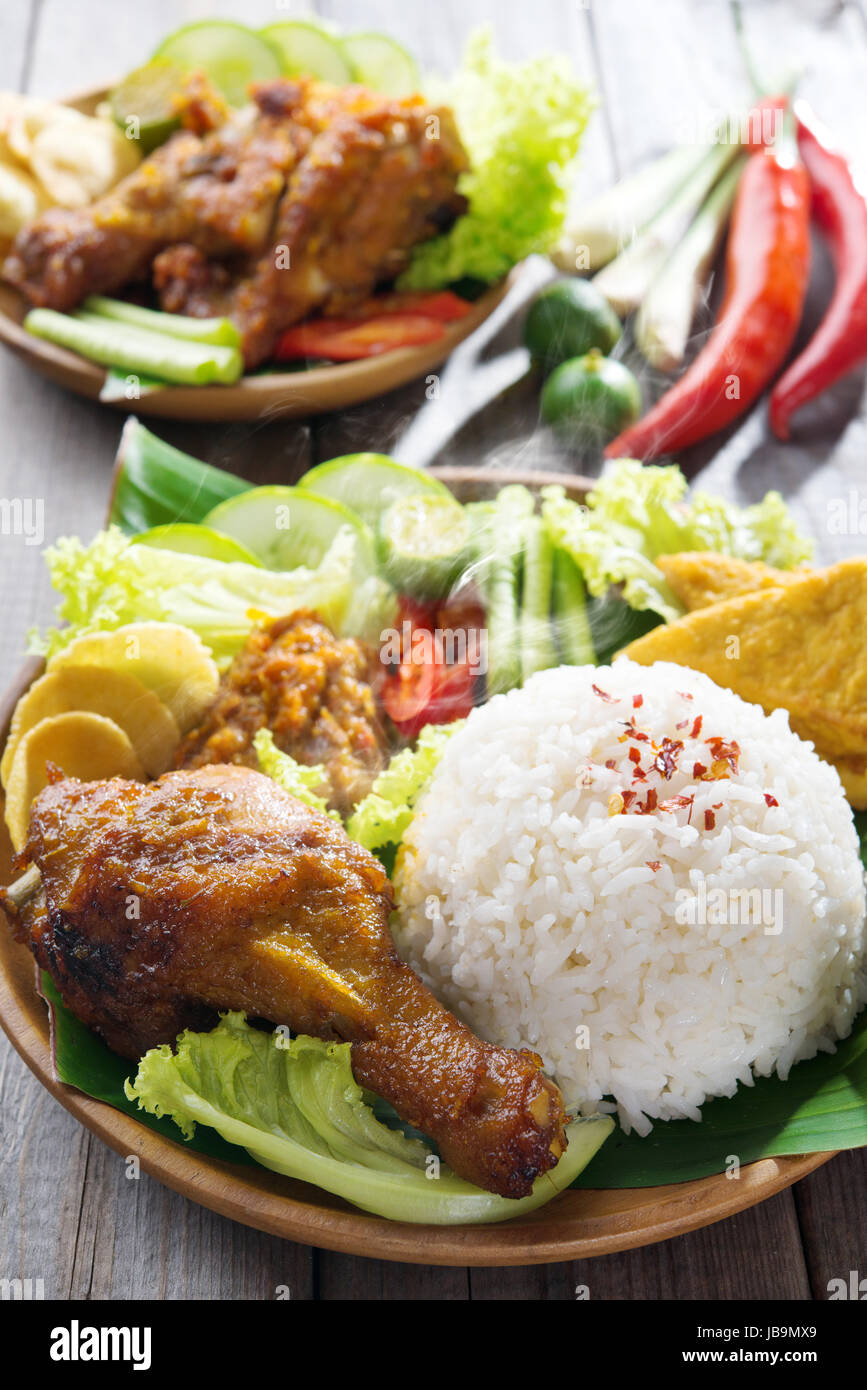Famous traditional Malay food. Delicious nasi ayam penyet with sambal belacan. Local flavor. Fresh hot with steam smoke. Stock Photo