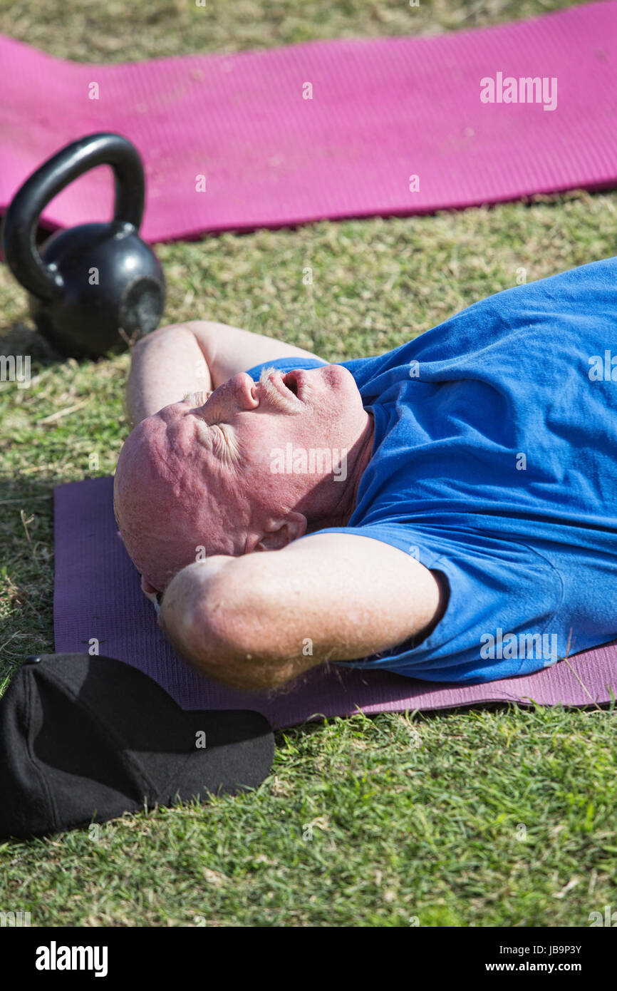 Exhausted man laying on mat after working out Stock Photo