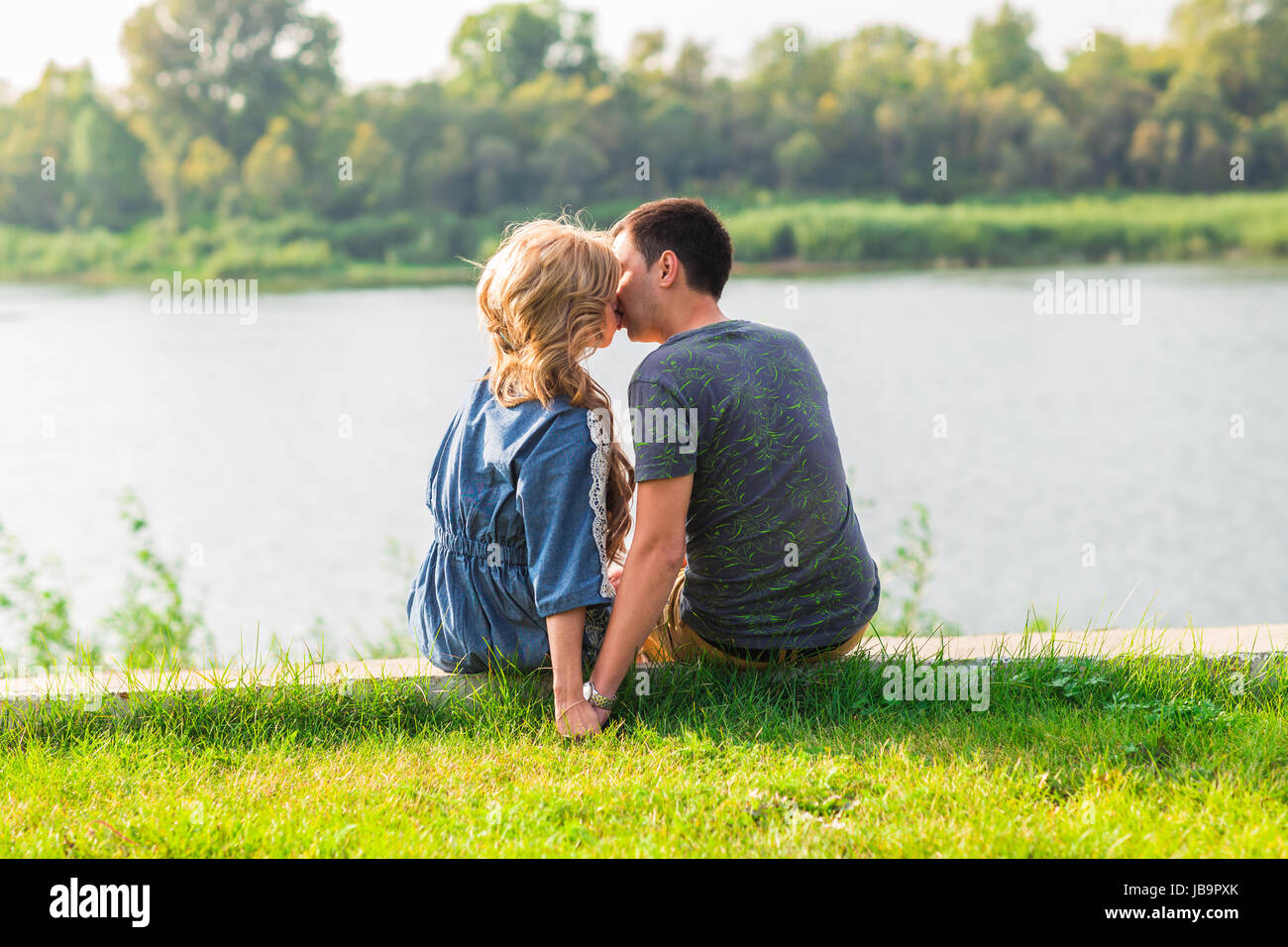 Beautiful lovers sitting on grass hi-res stock photography and