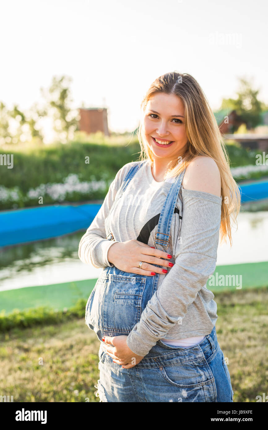 Pregnant woman hugging her belly outdoors Stock Photo - Alamy