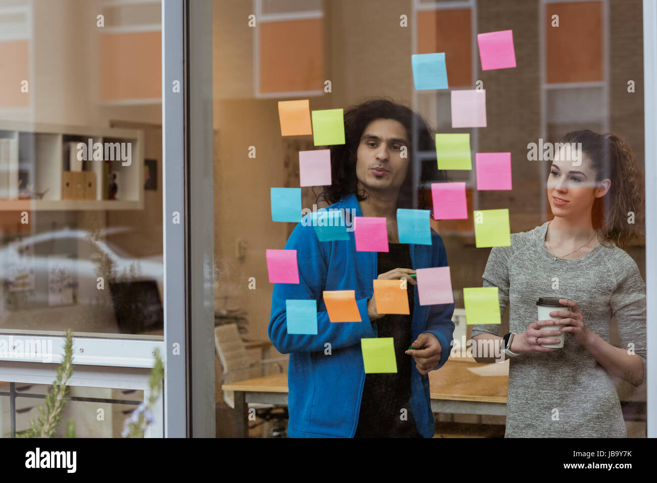 Business colleagues discussing over sticky notes in office Stock Photo ...
