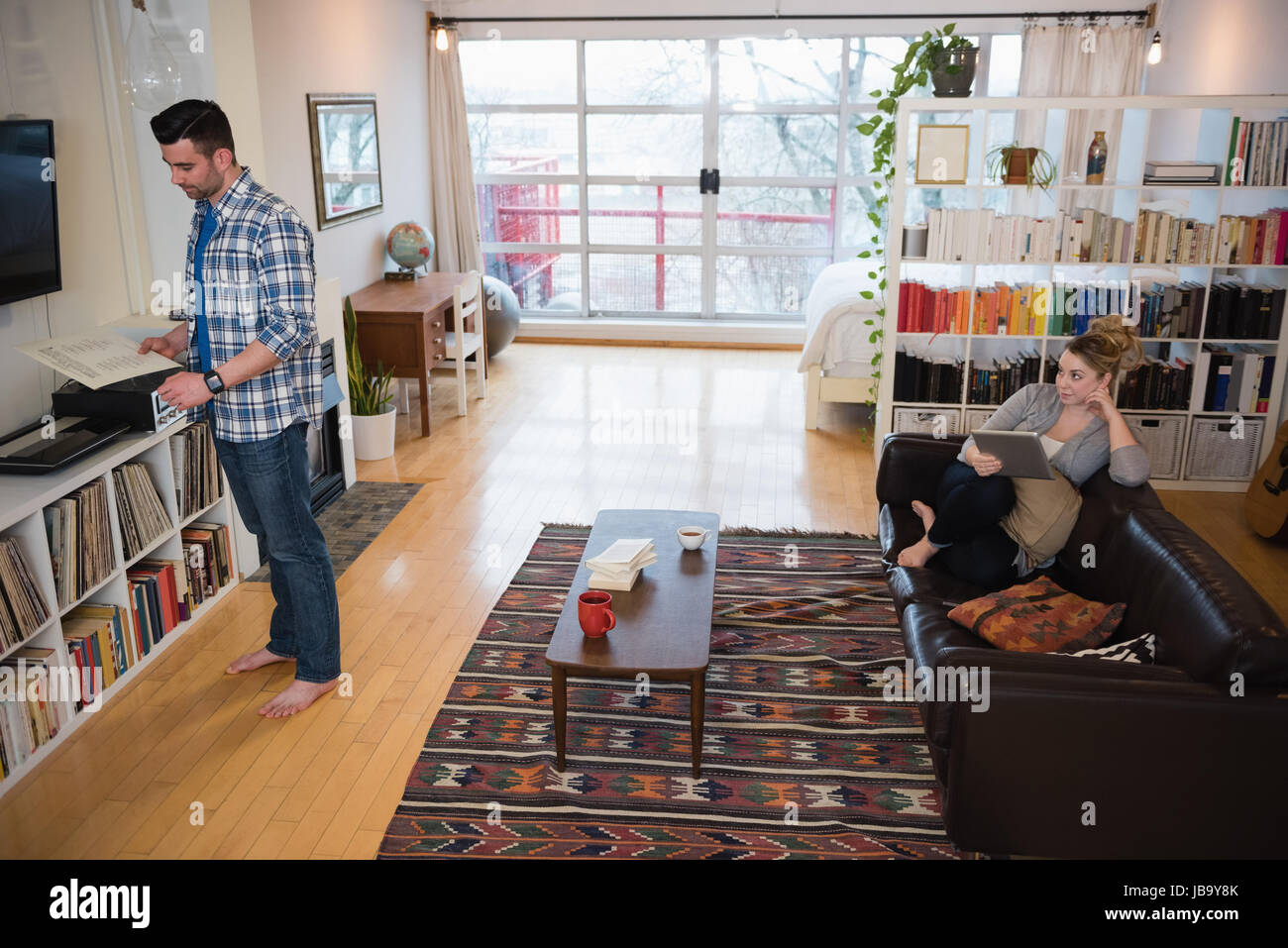 Man holding cd player while woman looking at him in living room Stock