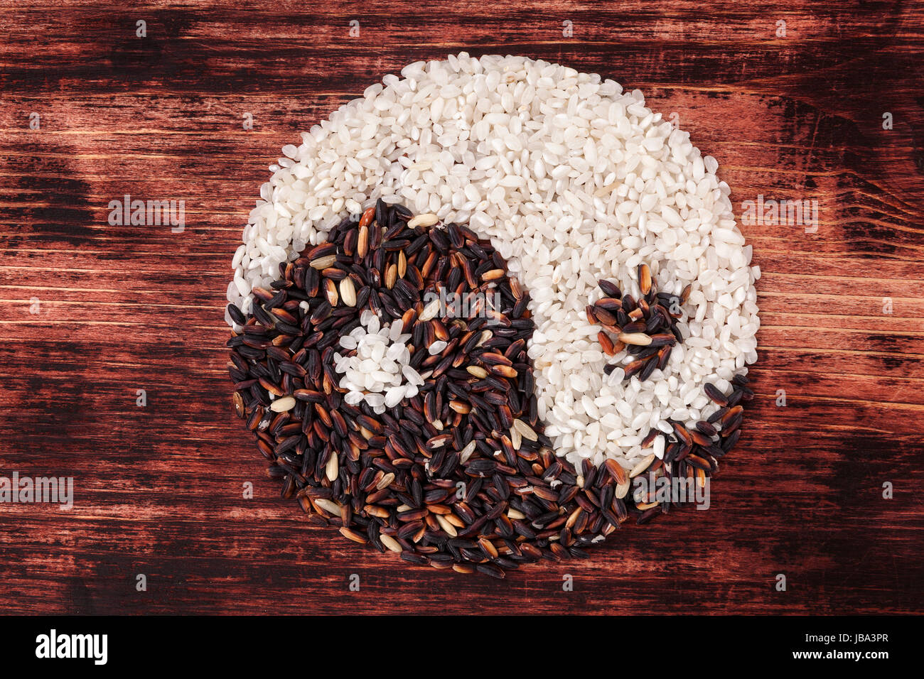 White and wild rice shaped as Yin yang symbol on dark wooden background ...