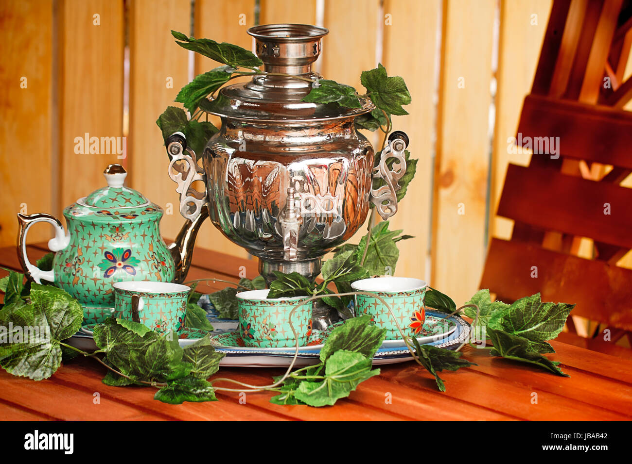 Beautiful large samovar, cups and a kettle are standing on a table in expectation of the guests. Stock Photo