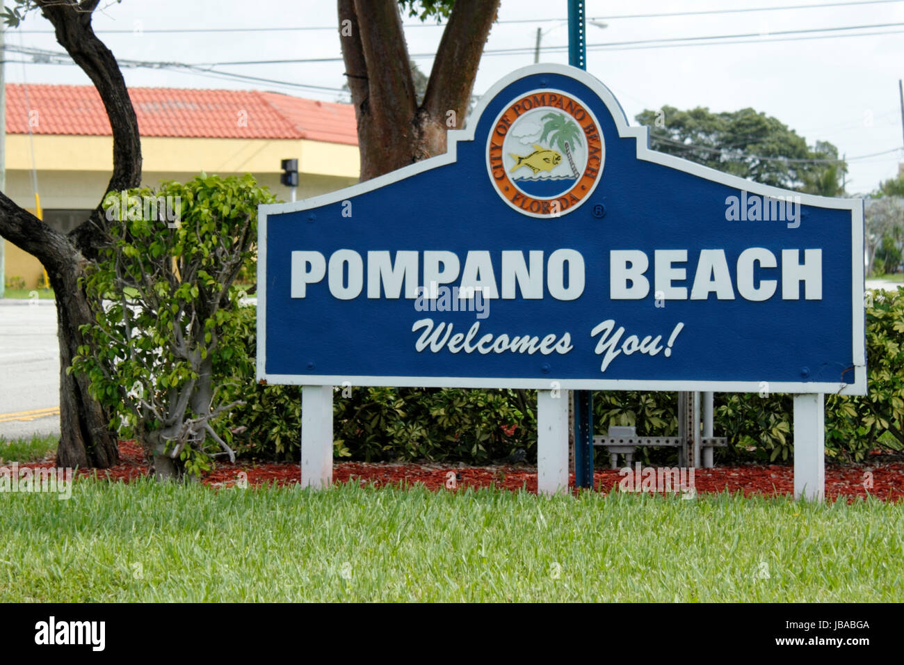 POMPANO BEACH, FLORIDA - JULY 1, 2013: Large white and blue welcome sign at the entrance to the City of Pompano Beach, Florida, population of 102,984 in 2012, that has a colorful tropical graphic. Stock Photo