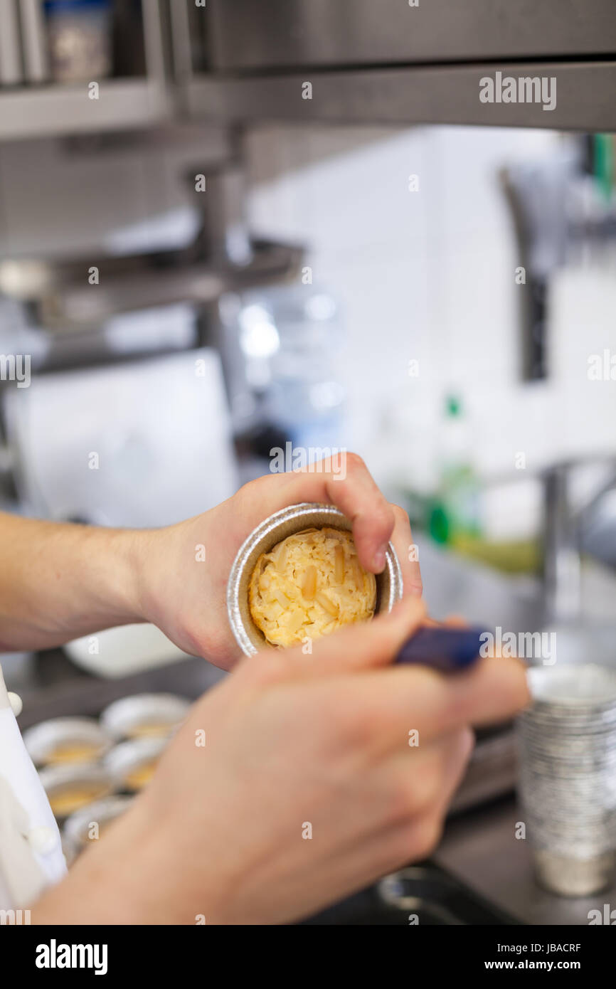 chefkoch löst frisch gebackene törtchen aus der form in der küche restaurant konditorei Stock Photo