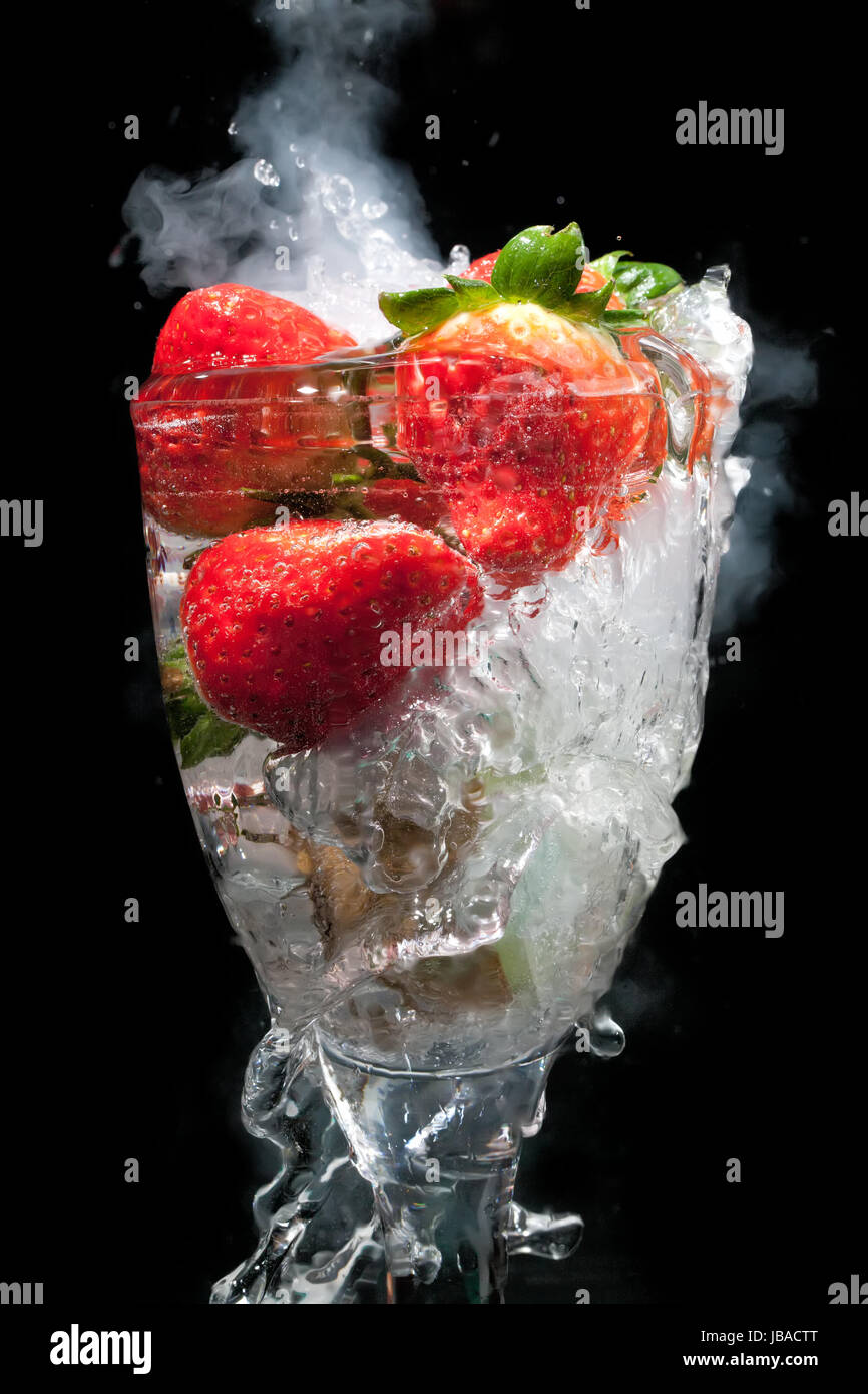 Fruit cocktail glass with steam and smoke, and water movement frozen, all on a black background