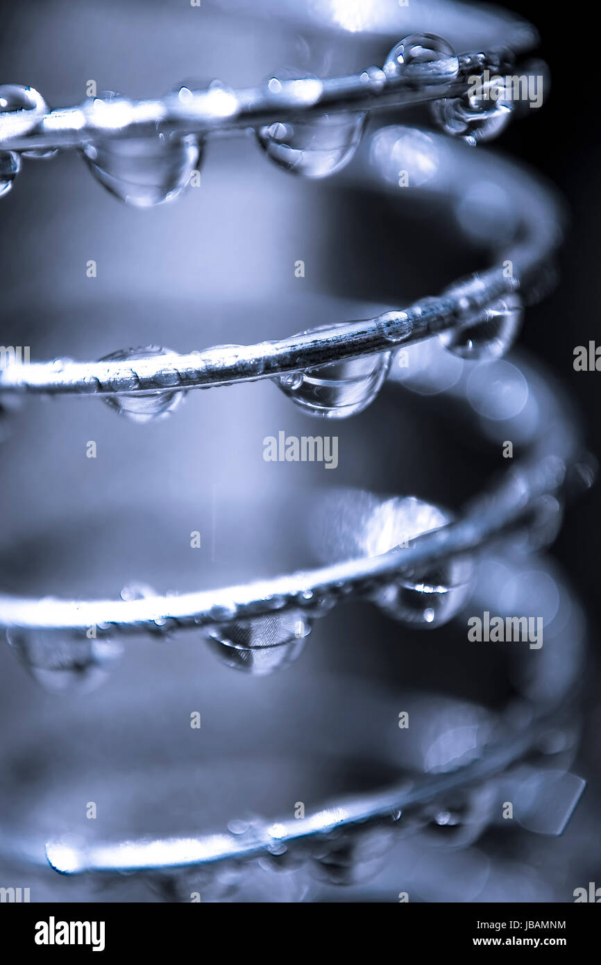 Gotas de agua bajando por una espiral de acero. Stock Photo