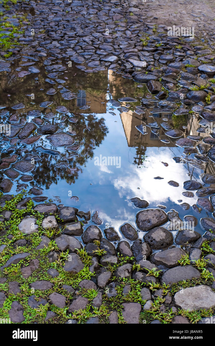 Reflections of buildings and blue sky over puddle after rain Stock ...
