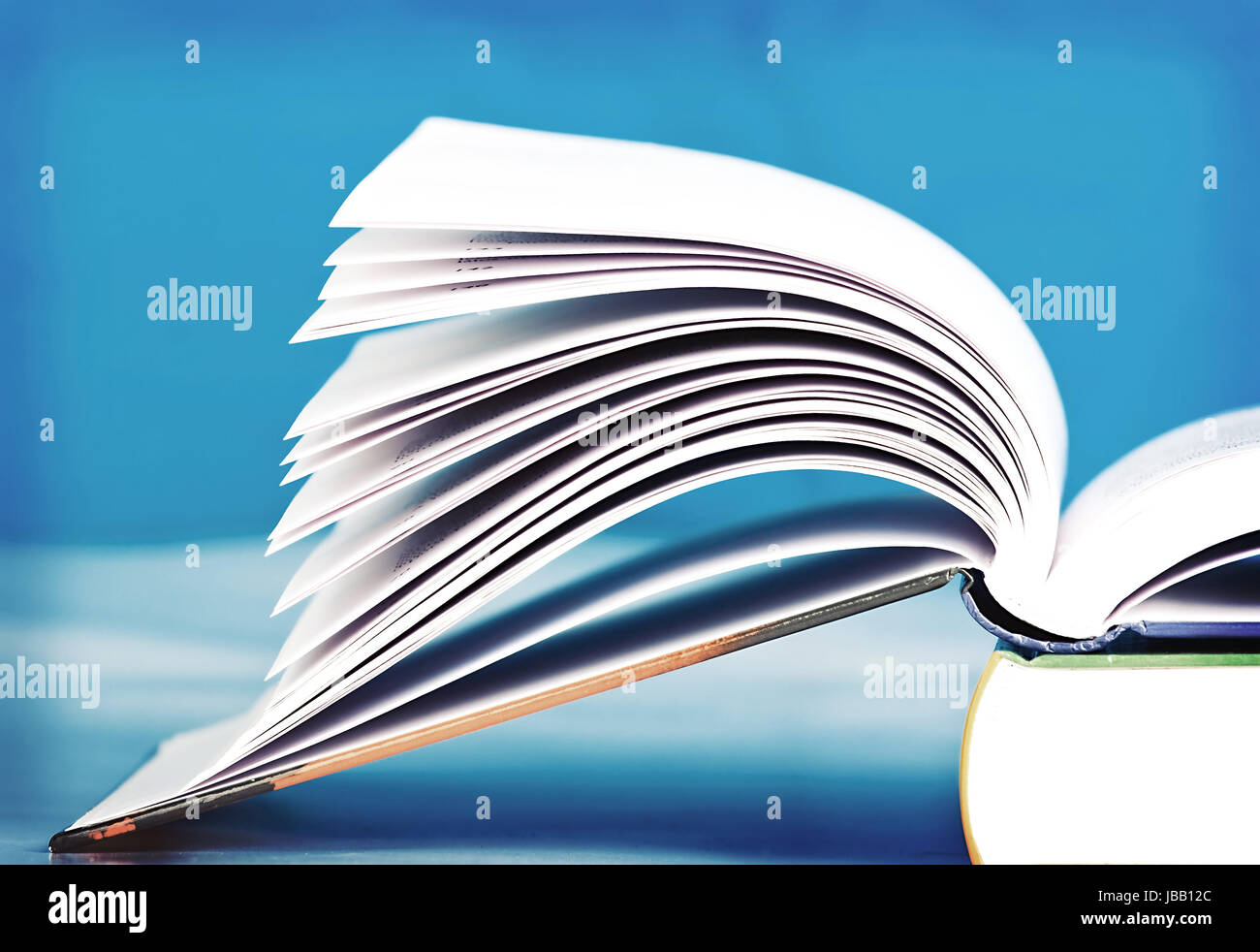 Open book in front of blue background Stock Photo - Alamy