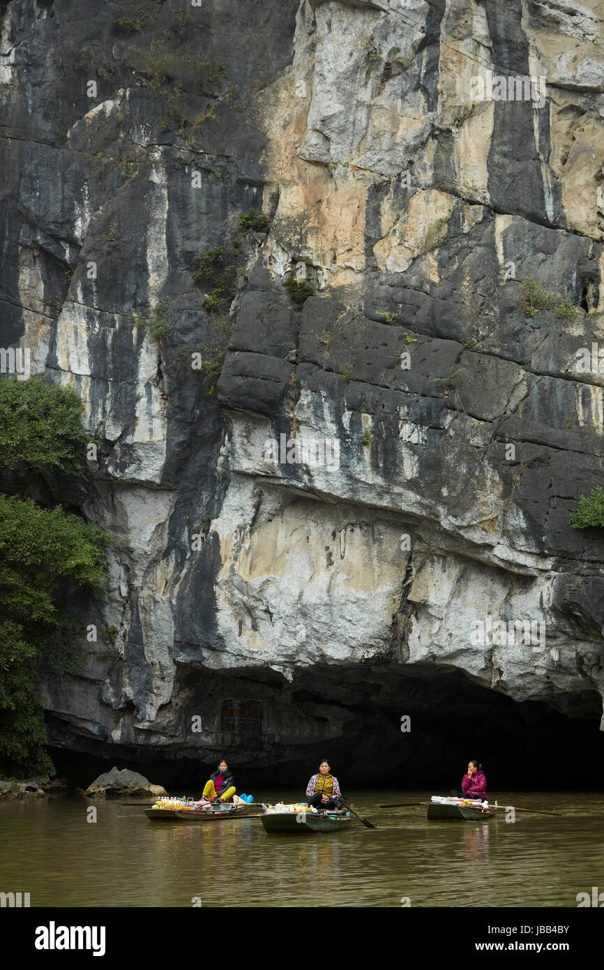 Hawkers with floating shops coming out of cave on on Tam Coc (three caves) boat trip on Ngo Dong River, (UNESCO World Herritage Area), near Ninh Binh, Stock Photo