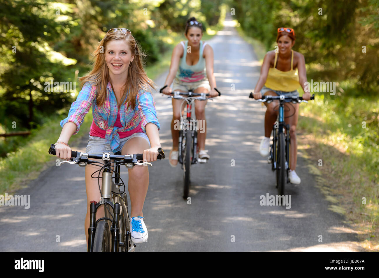 Three female friends riding bikes in park enjoy summer sport Stock Photo -  Alamy