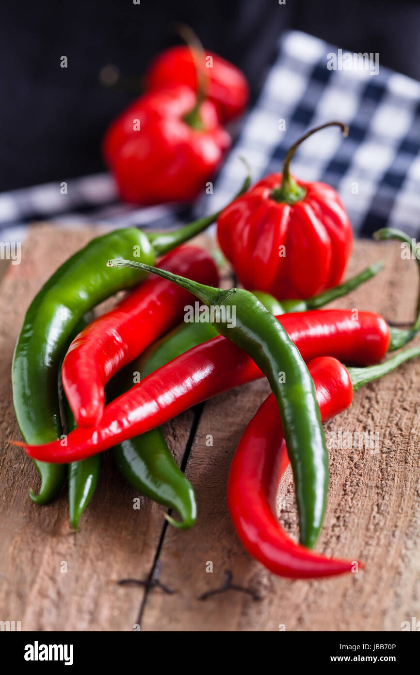 Closeup of red and green chili peppers on wooden board surface with ...